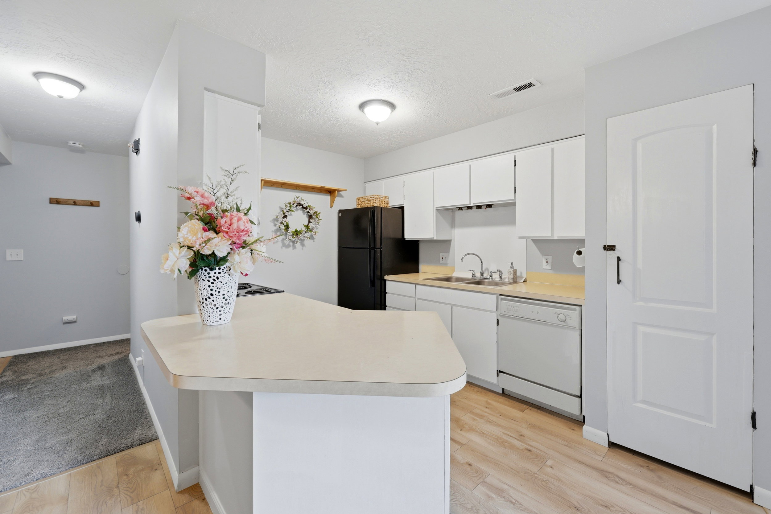 Kitchen featuring white cabinetry, black appliances, a double-basin sink, and wood-finish flooring