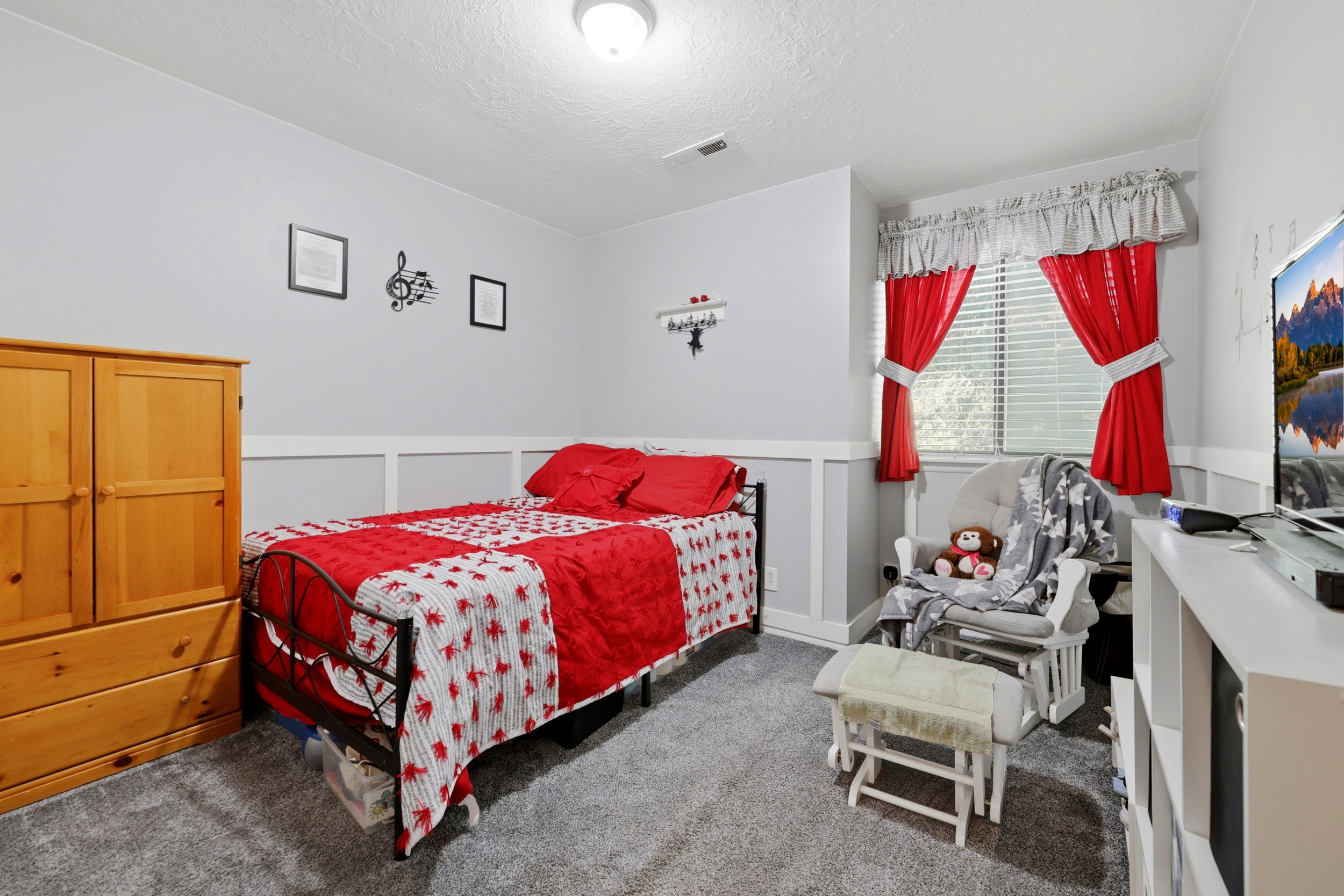 Interior room featuring grey carpet flooring, light grey walls with white wainscoting, and a window with blinds