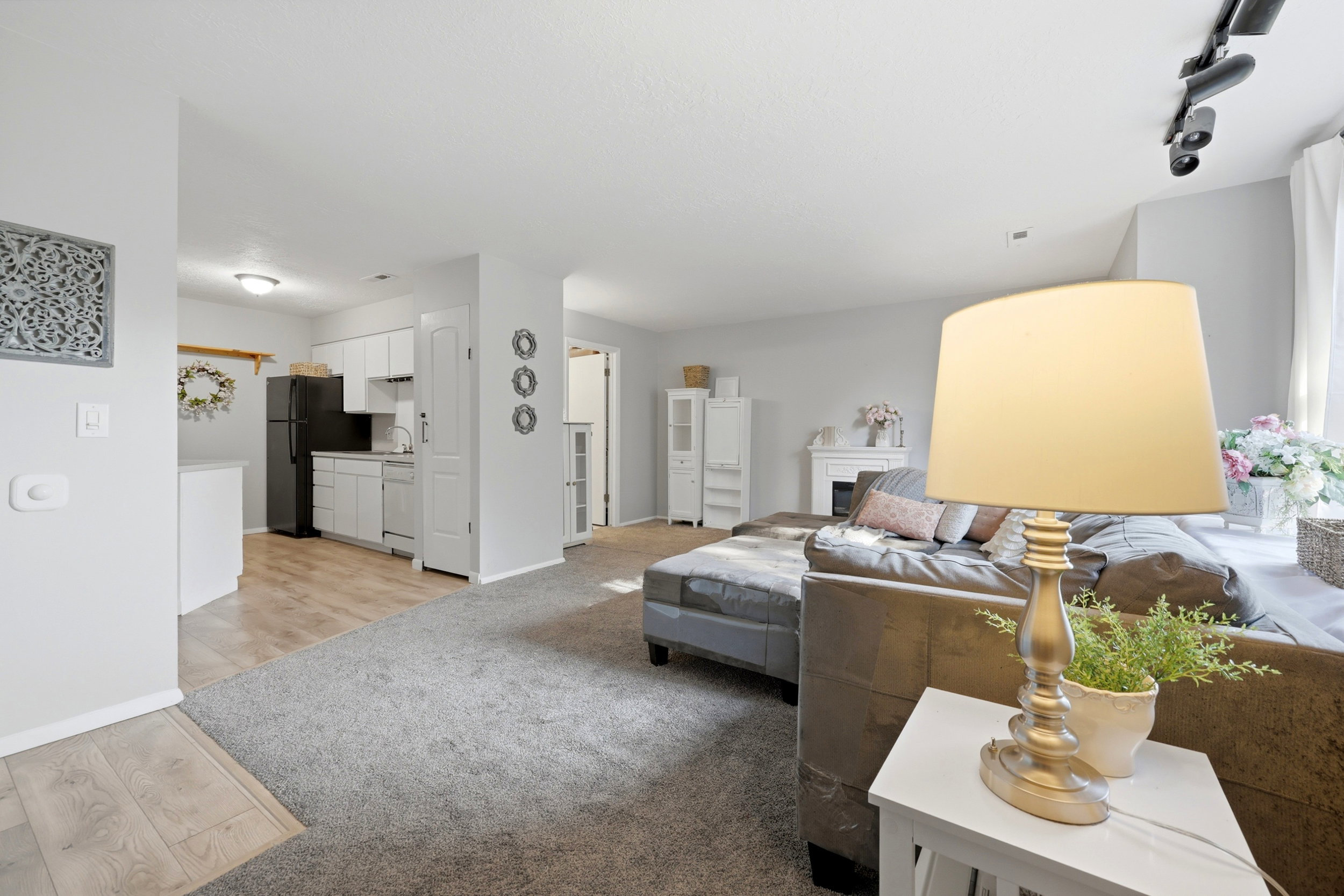 Open-concept living area featuring light gray wall paint, gray carpeting, and wood-finish flooring