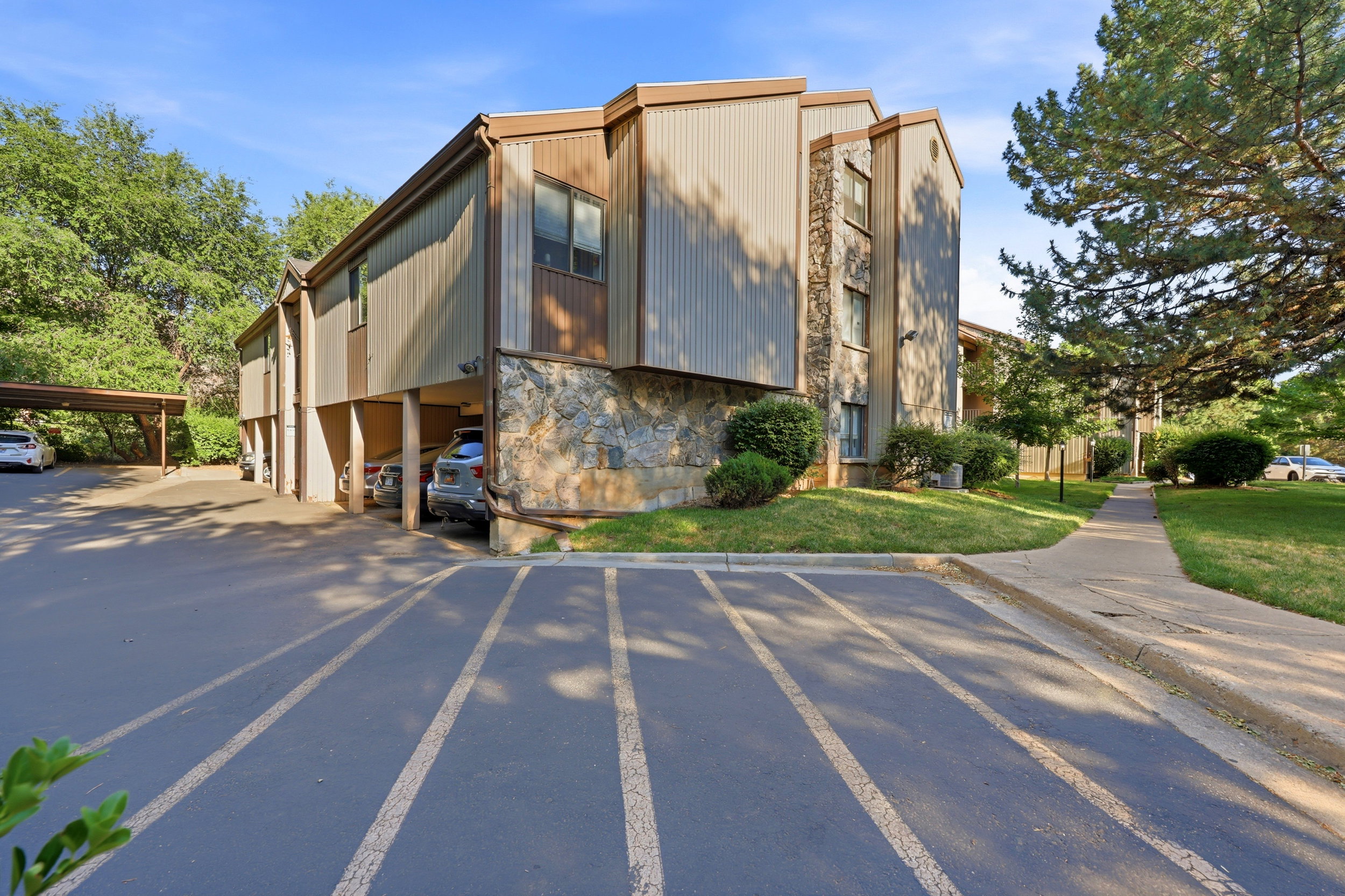 Multi-level residential building featuring stone facade elements, vertical siding, and a covered parking area