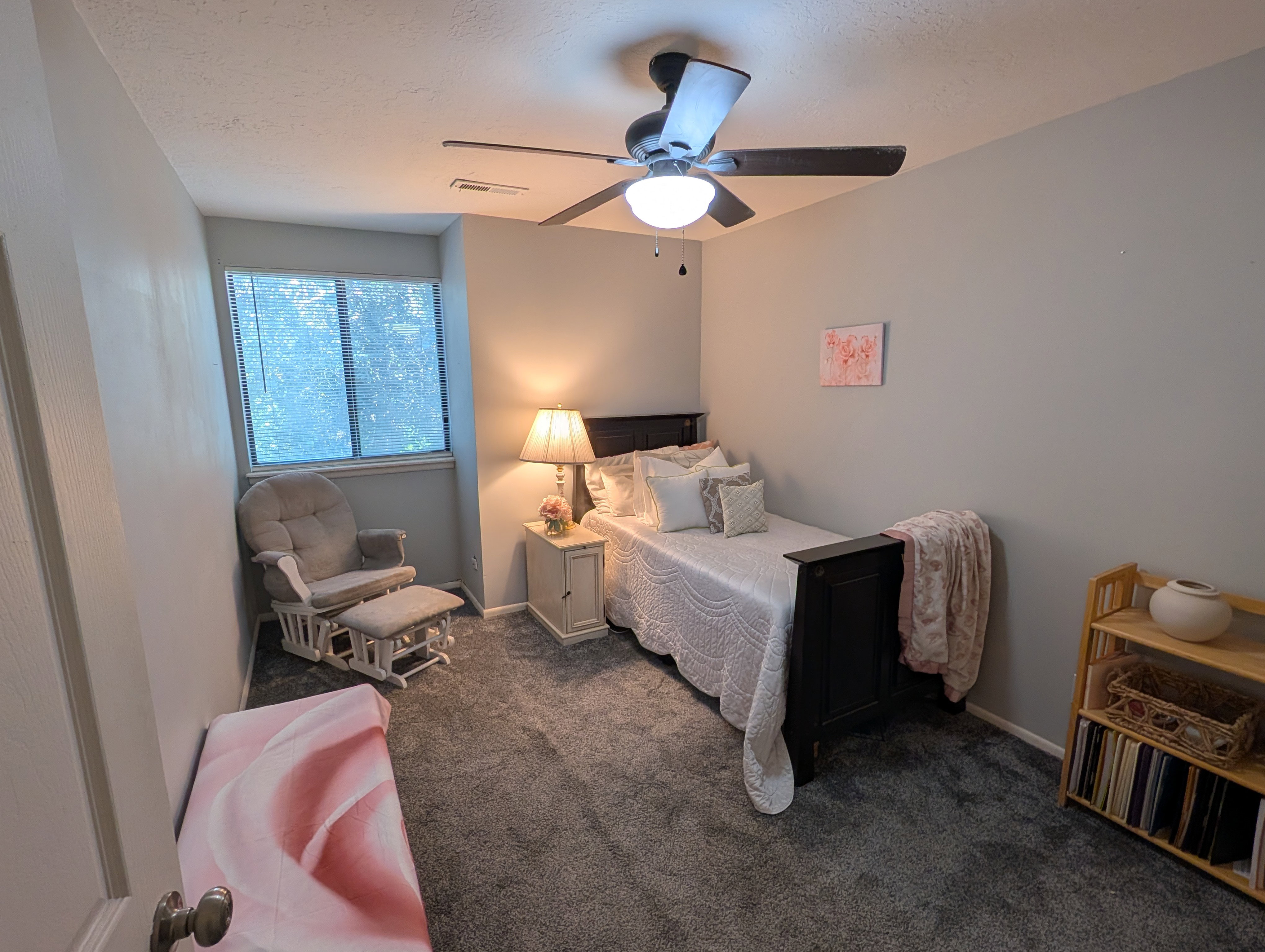 Carpeted room featuring a ceiling fan with integrated lighting, a window, and light gray wall tones