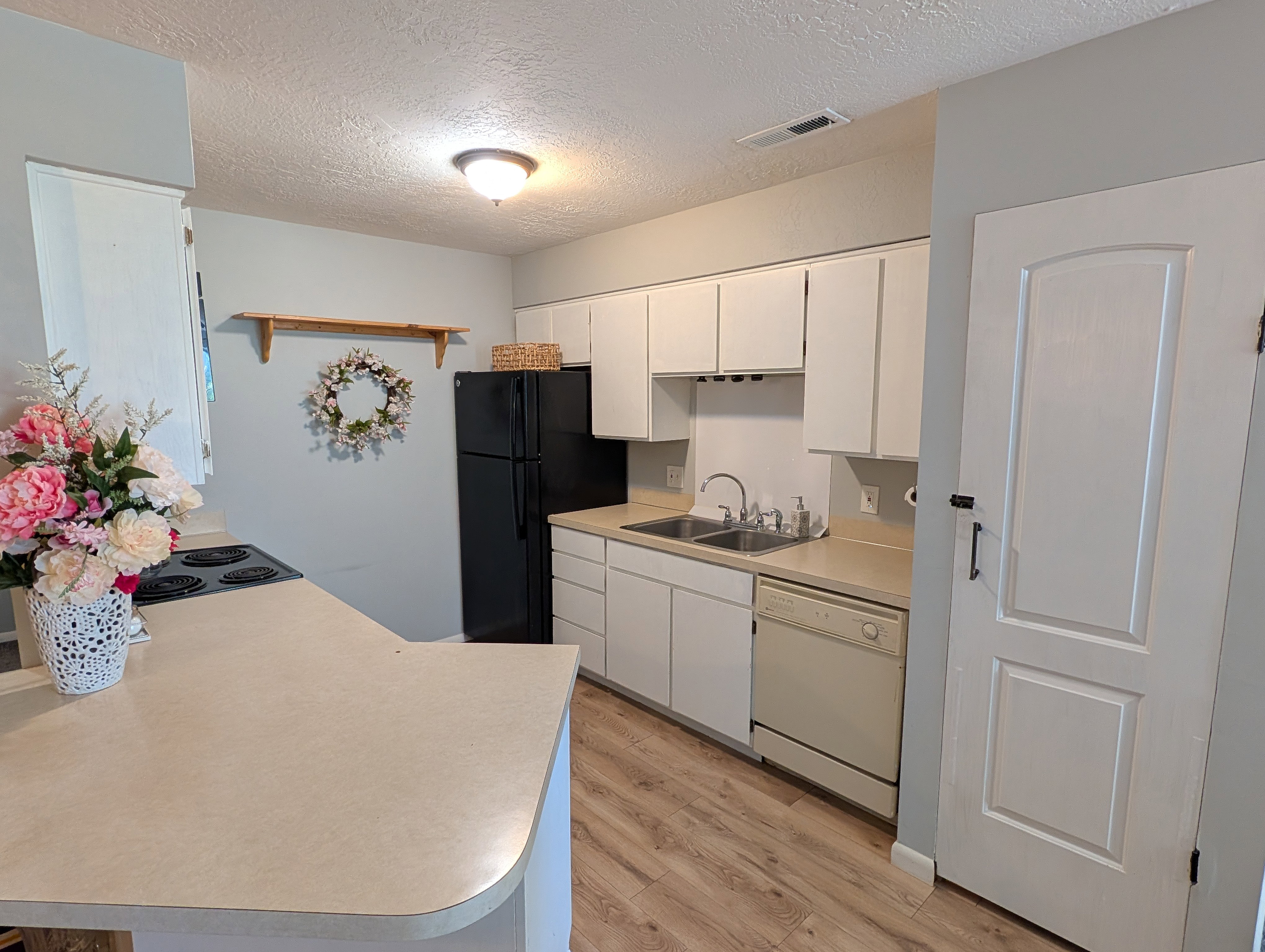 Kitchen featuring white cabinetry, light-toned countertops, and wood-finish flooring