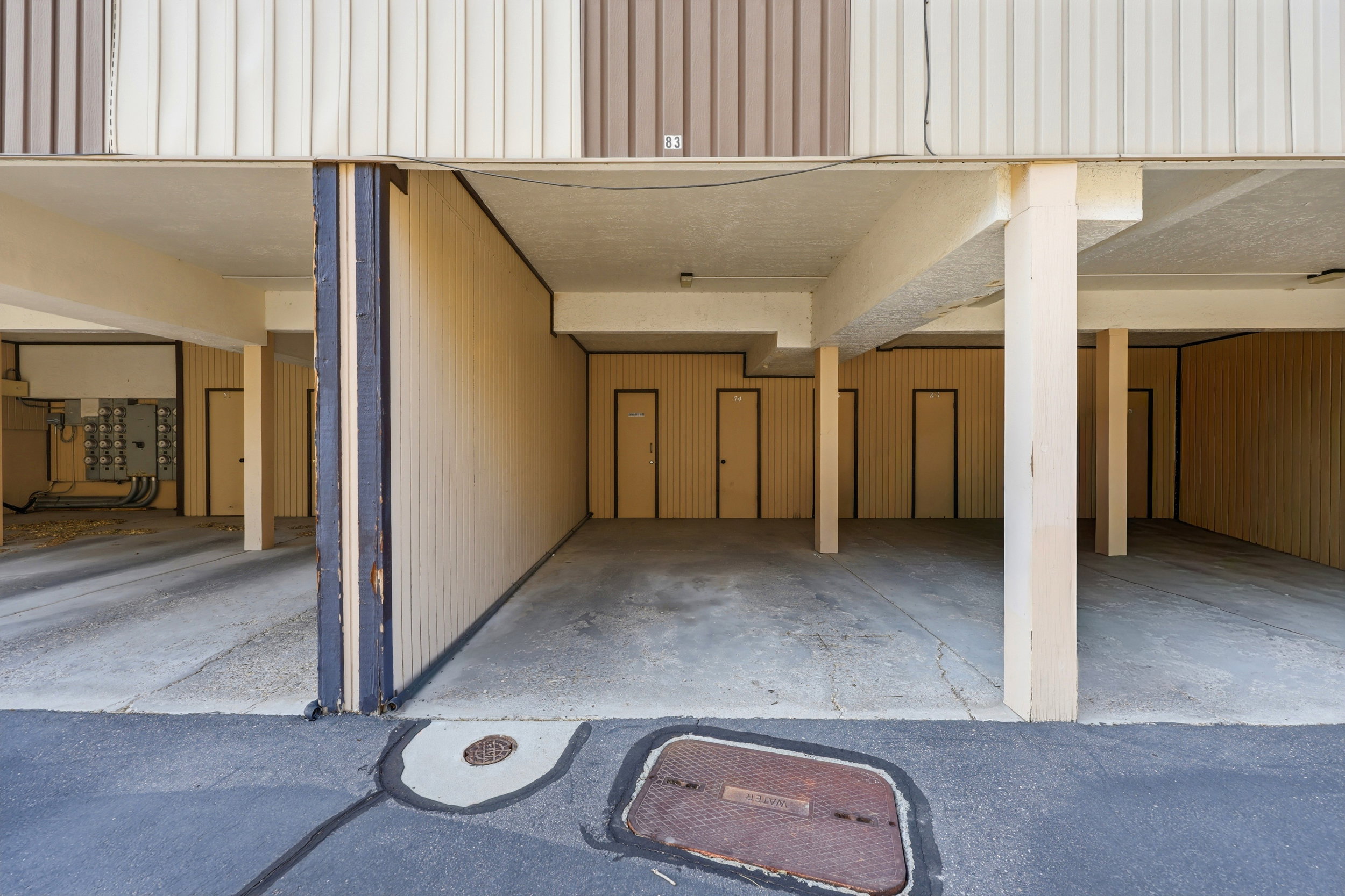 Covered parking area featuring concrete flooring and multiple access doors