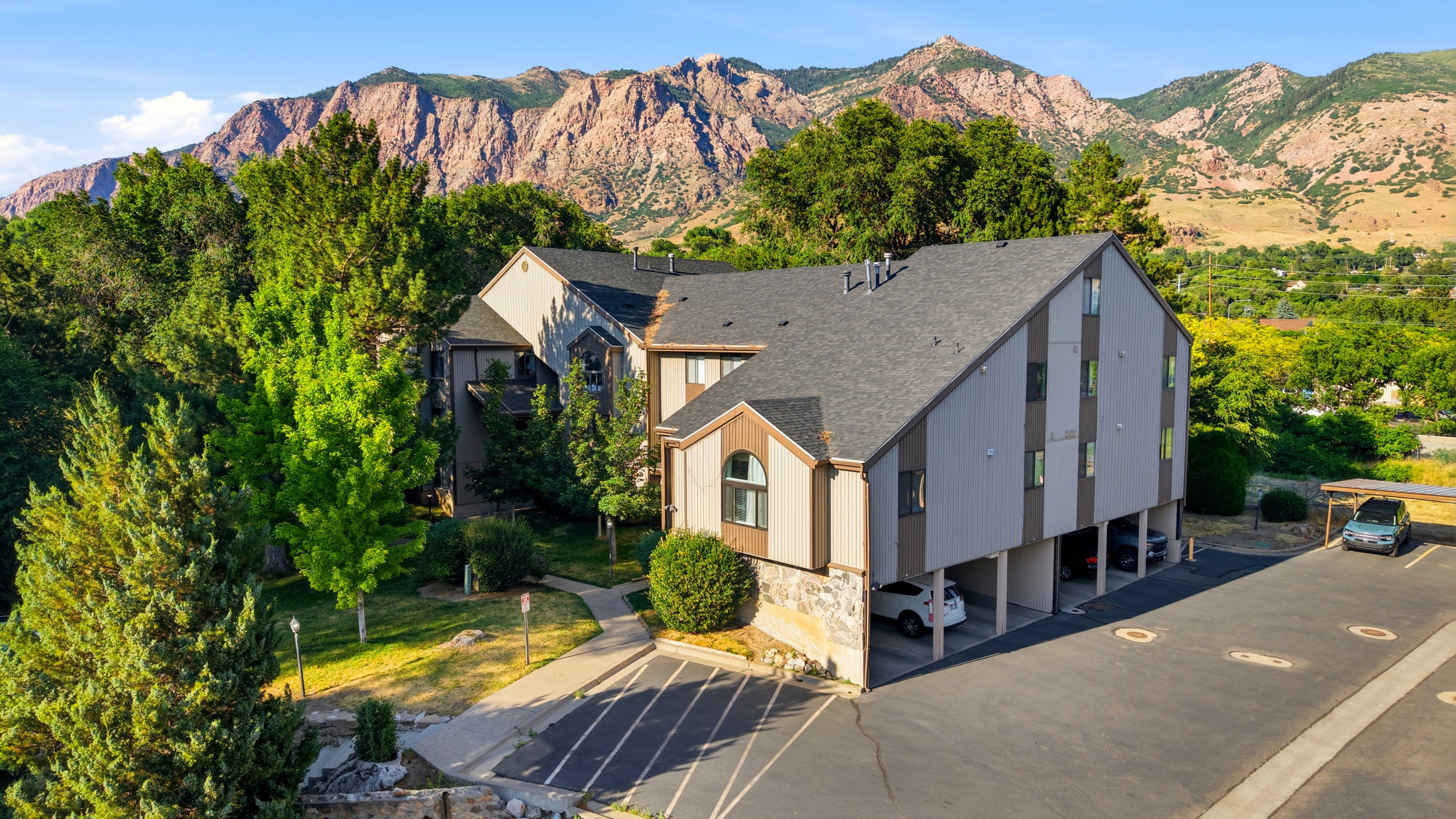 Multi-story residential building featuring a stone and siding exterior, sloped roofline, and integrated covered parking