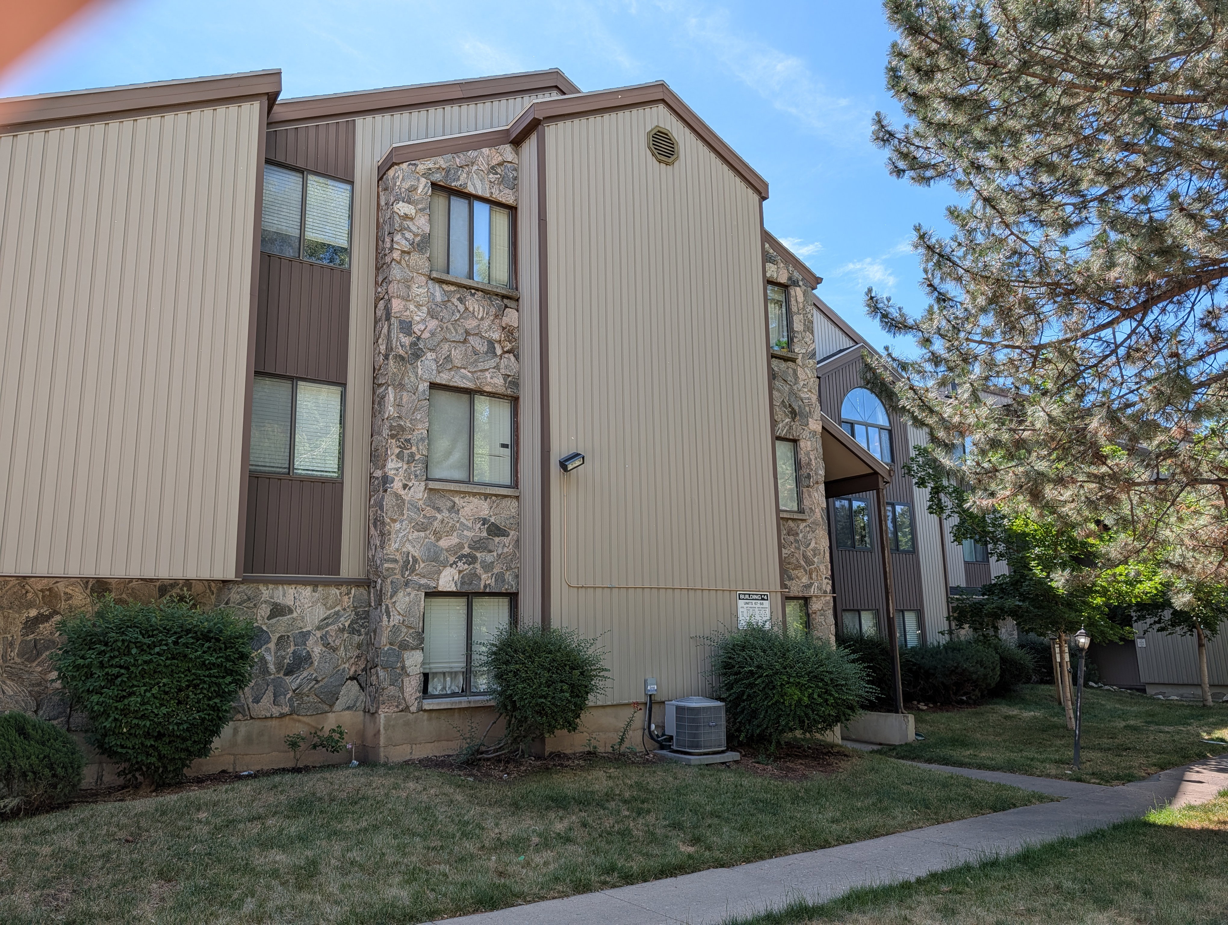 Multi-story building featuring tan vertical siding and stone veneer accents