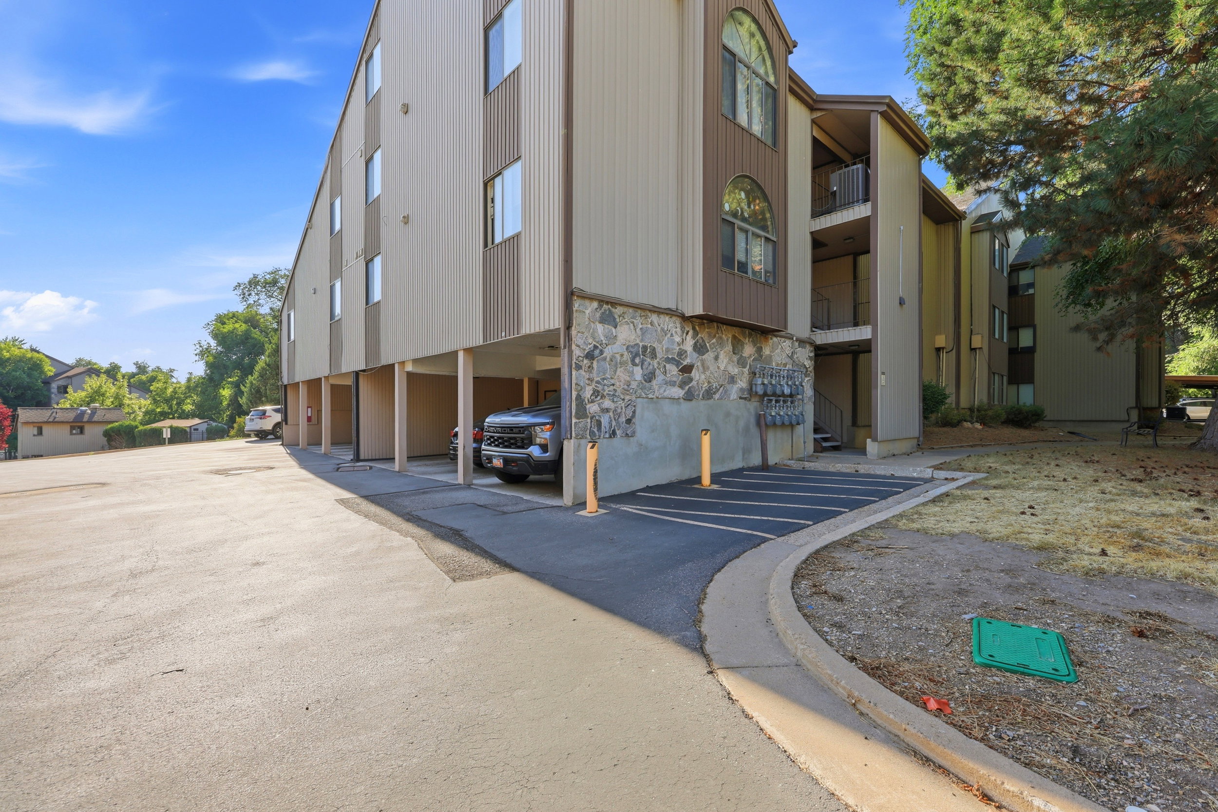 Multi-story building exterior featuring a stone facade base, vertical siding, and multiple balconies