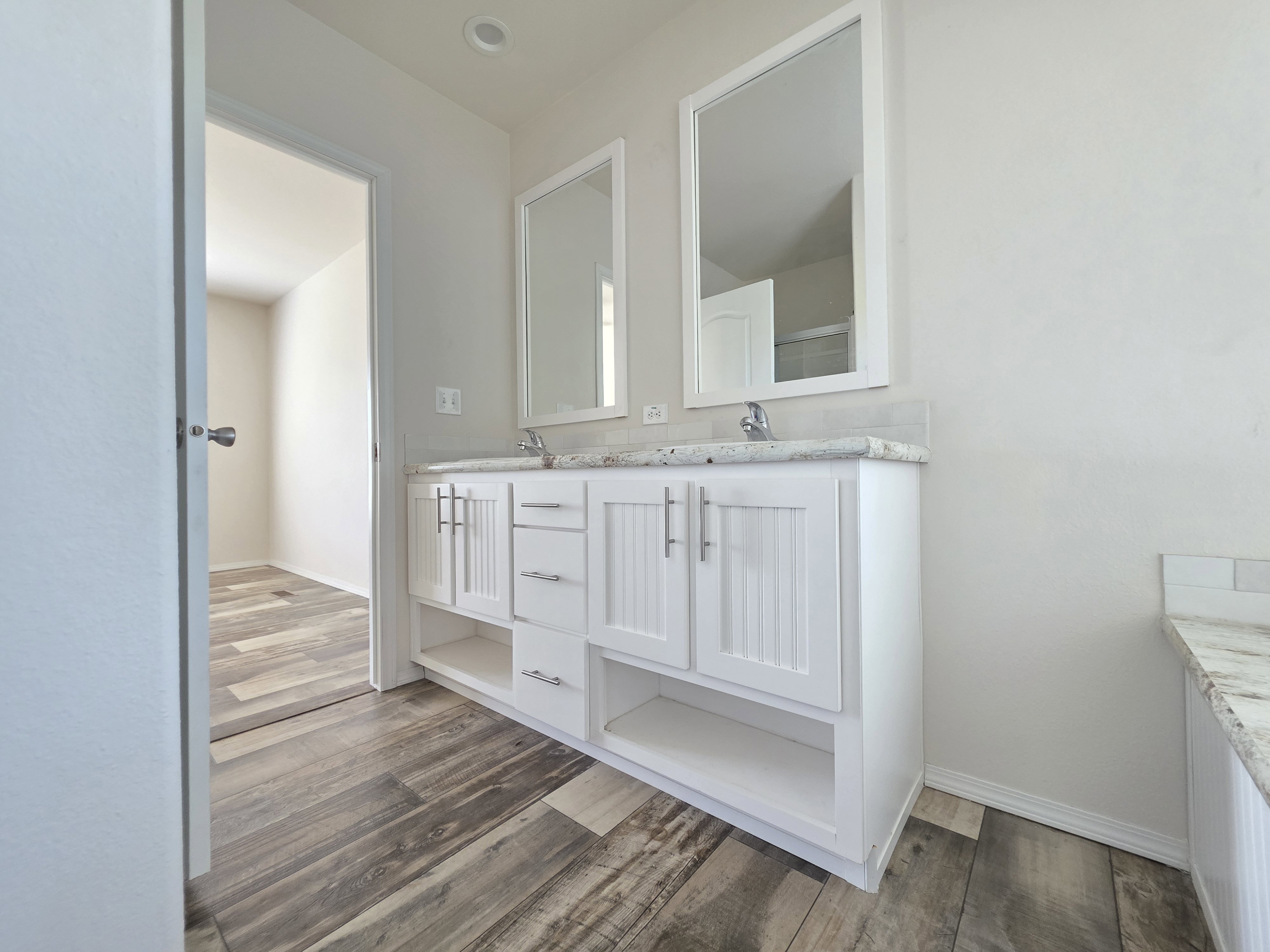 Double vanity with white cabinetry and integrated storage shelving