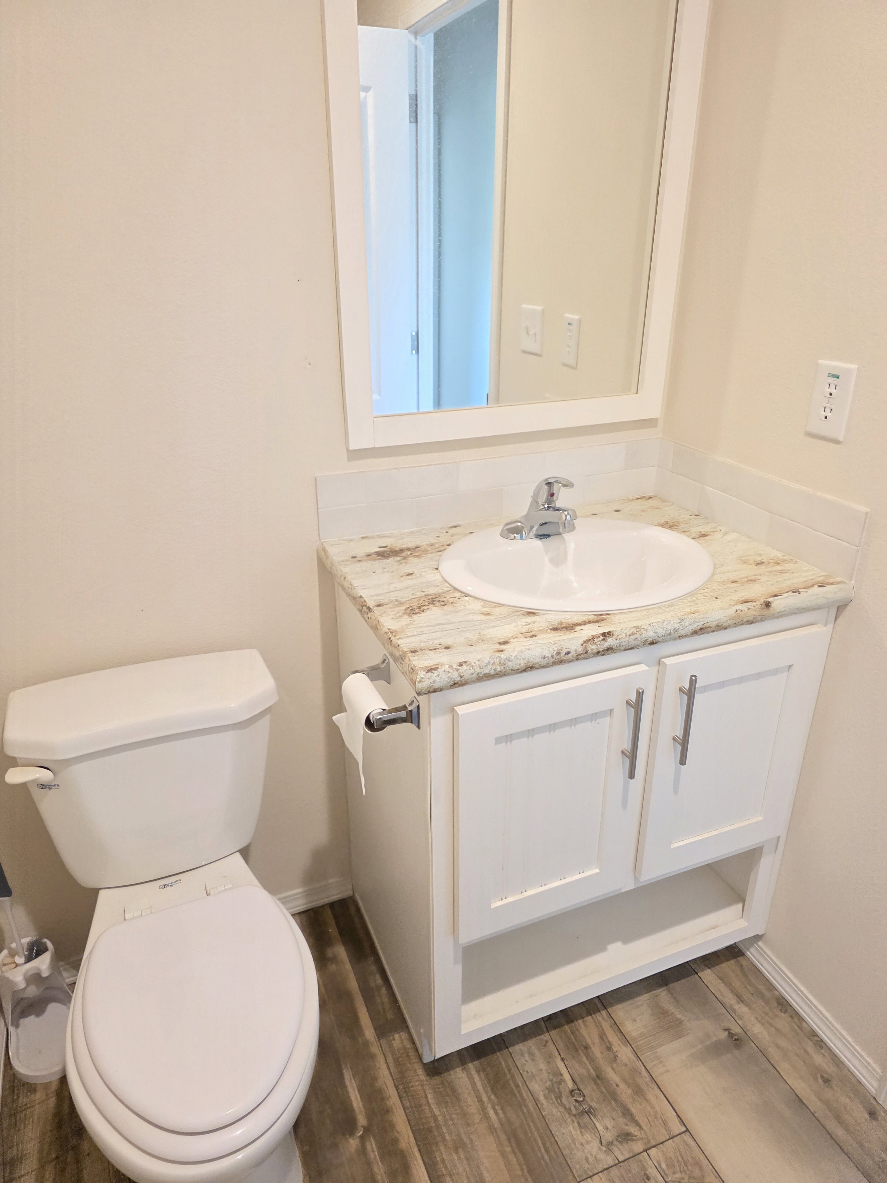 Bathroom vanity featuring a granite countertop, white under-mount sink, and chrome faucet