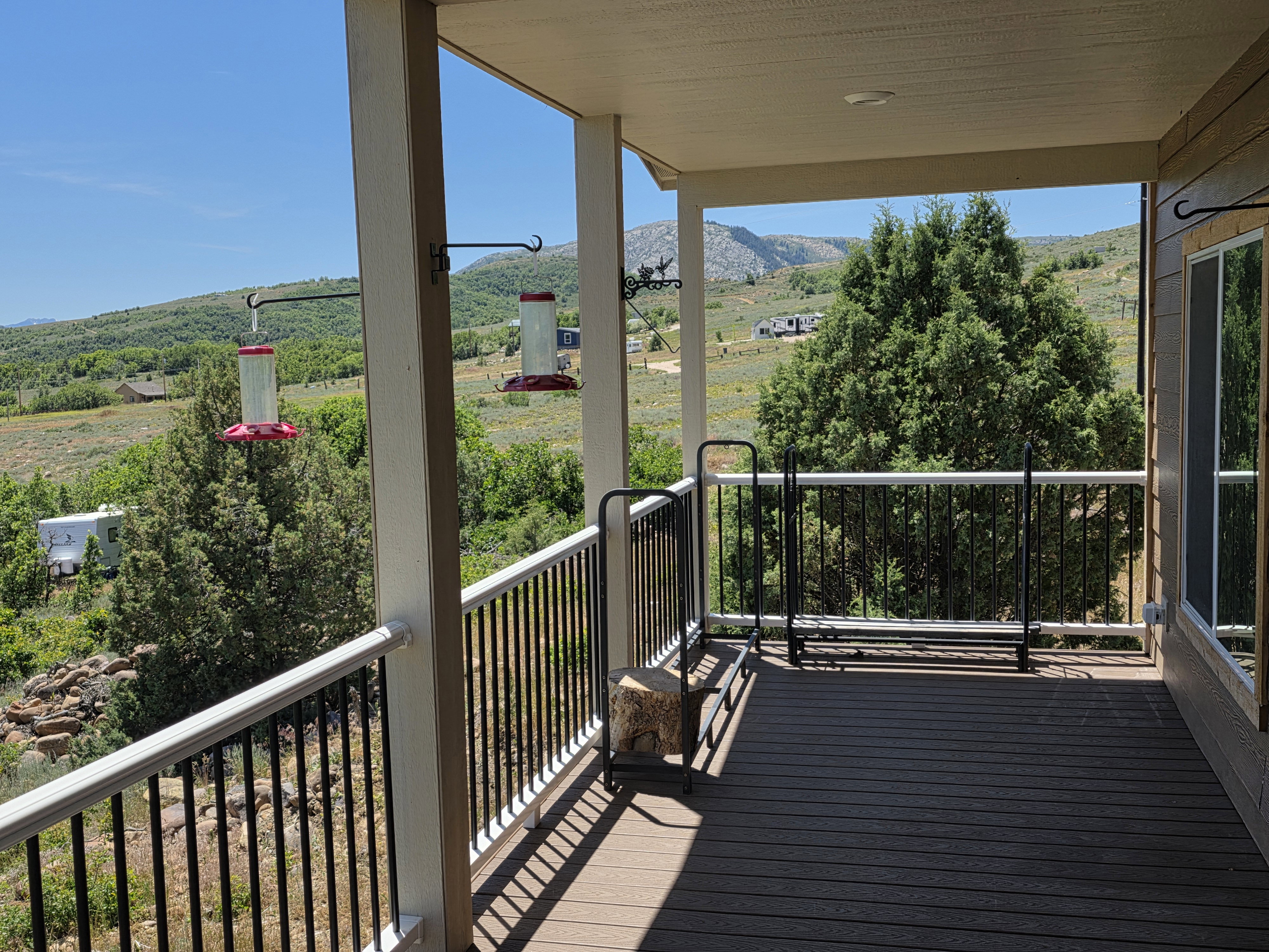 Covered outdoor deck featuring composite flooring and a white and black railing system