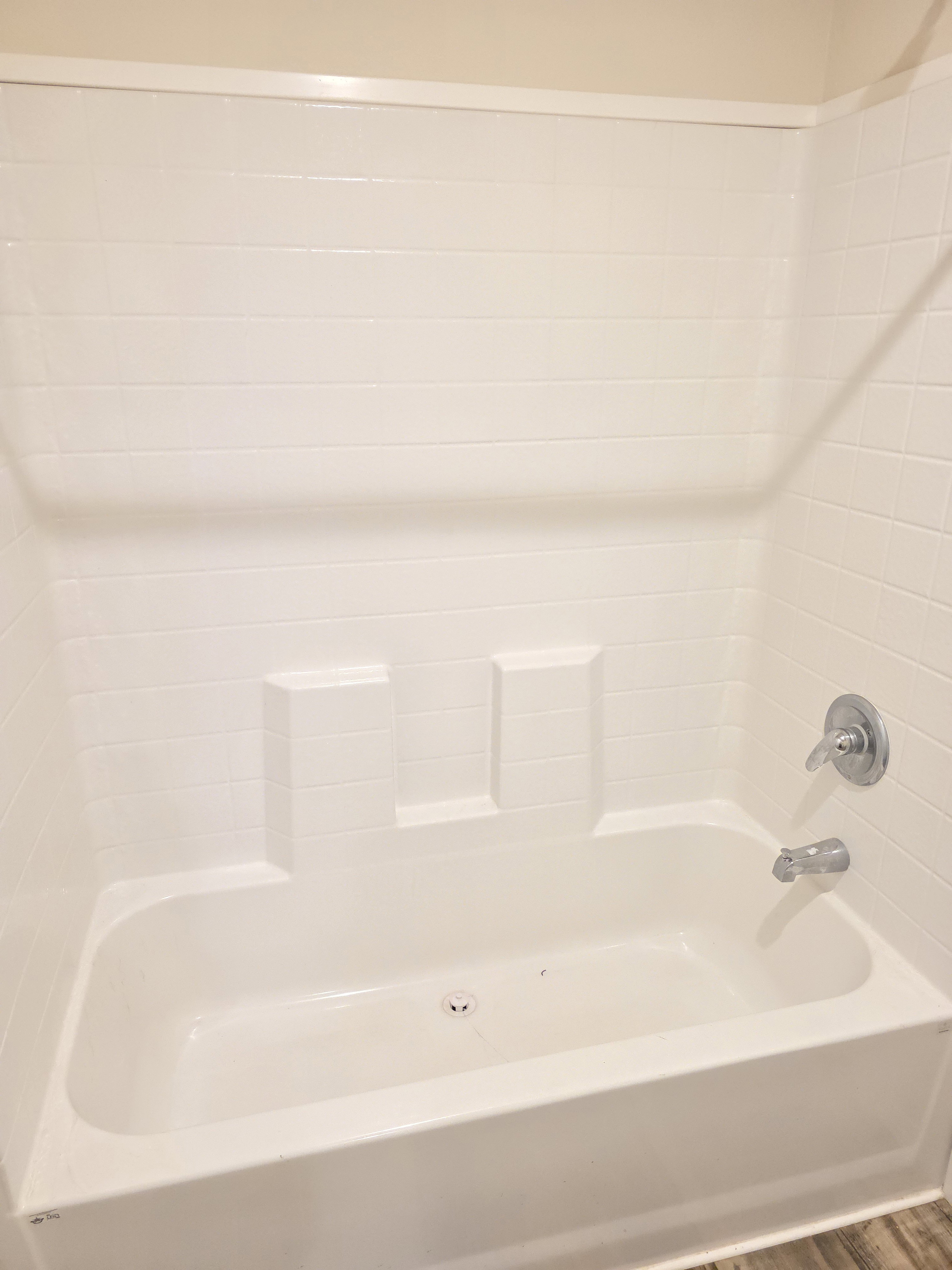 White tub and shower combination with integrated shelving