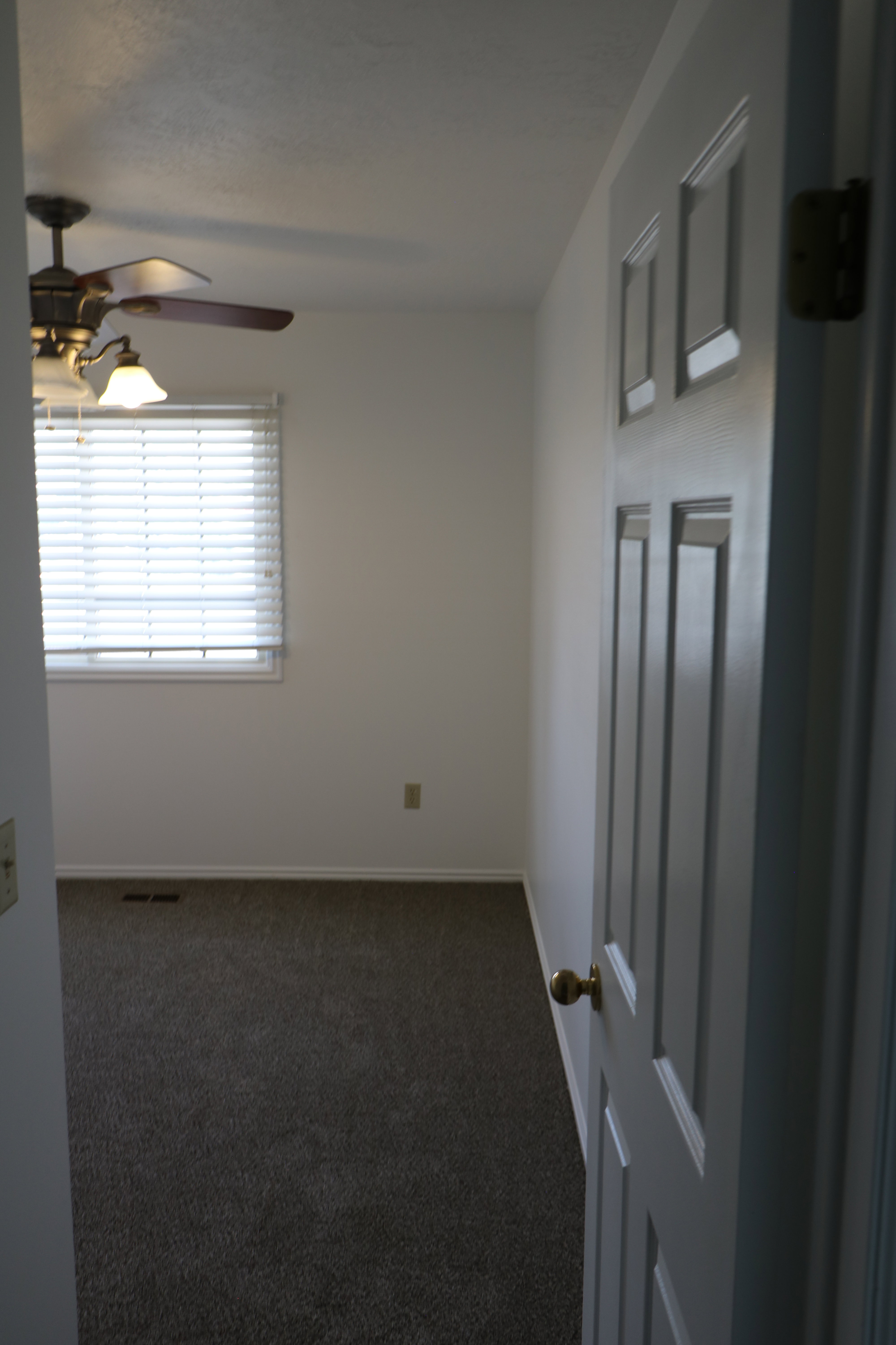 Bedroom featuring carpeted flooring, a window with blinds, and a ceiling fan with integrated lighting