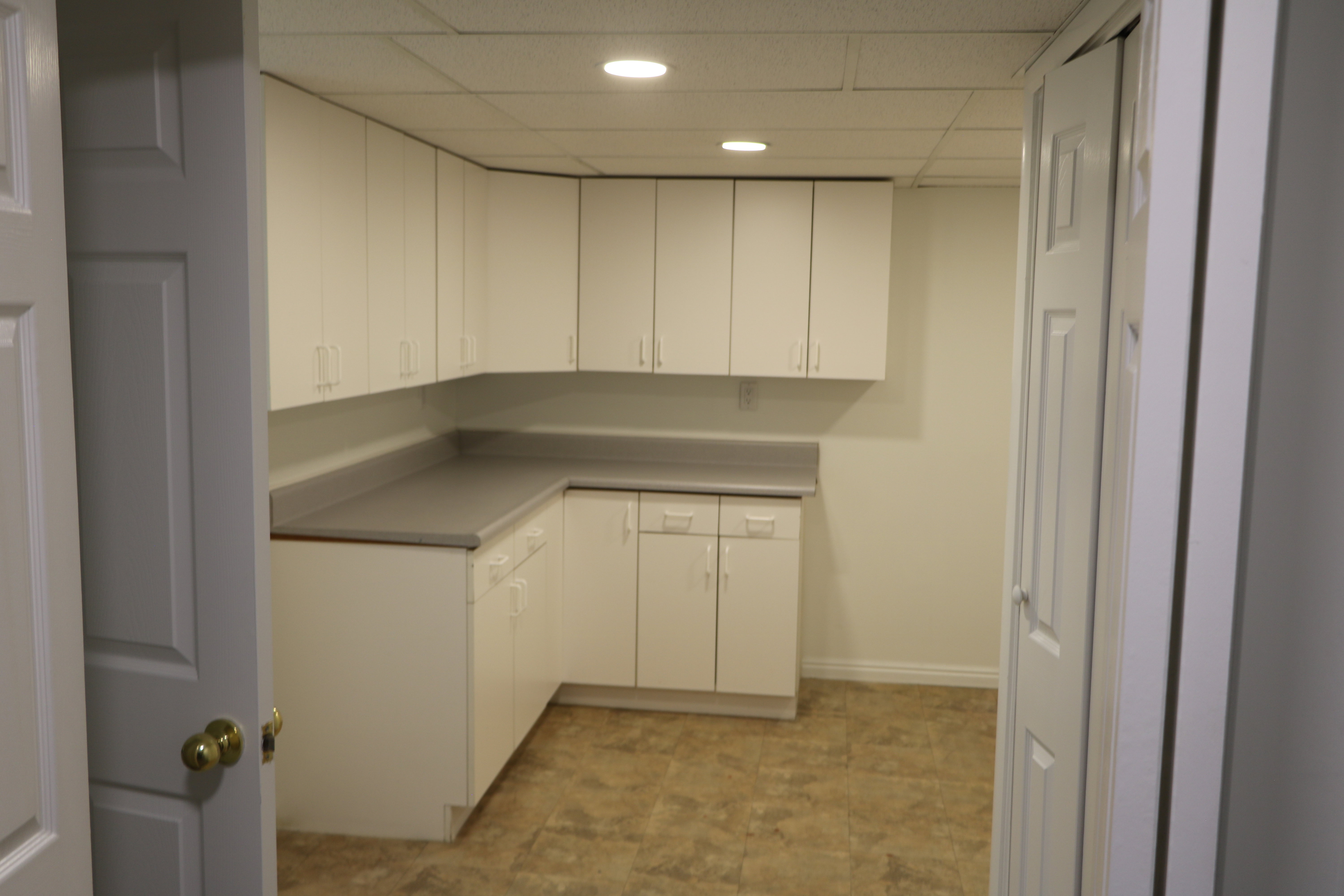 Utility room featuring extensive white cabinetry, a light gray countertop, recessed lighting, and resilient flooring