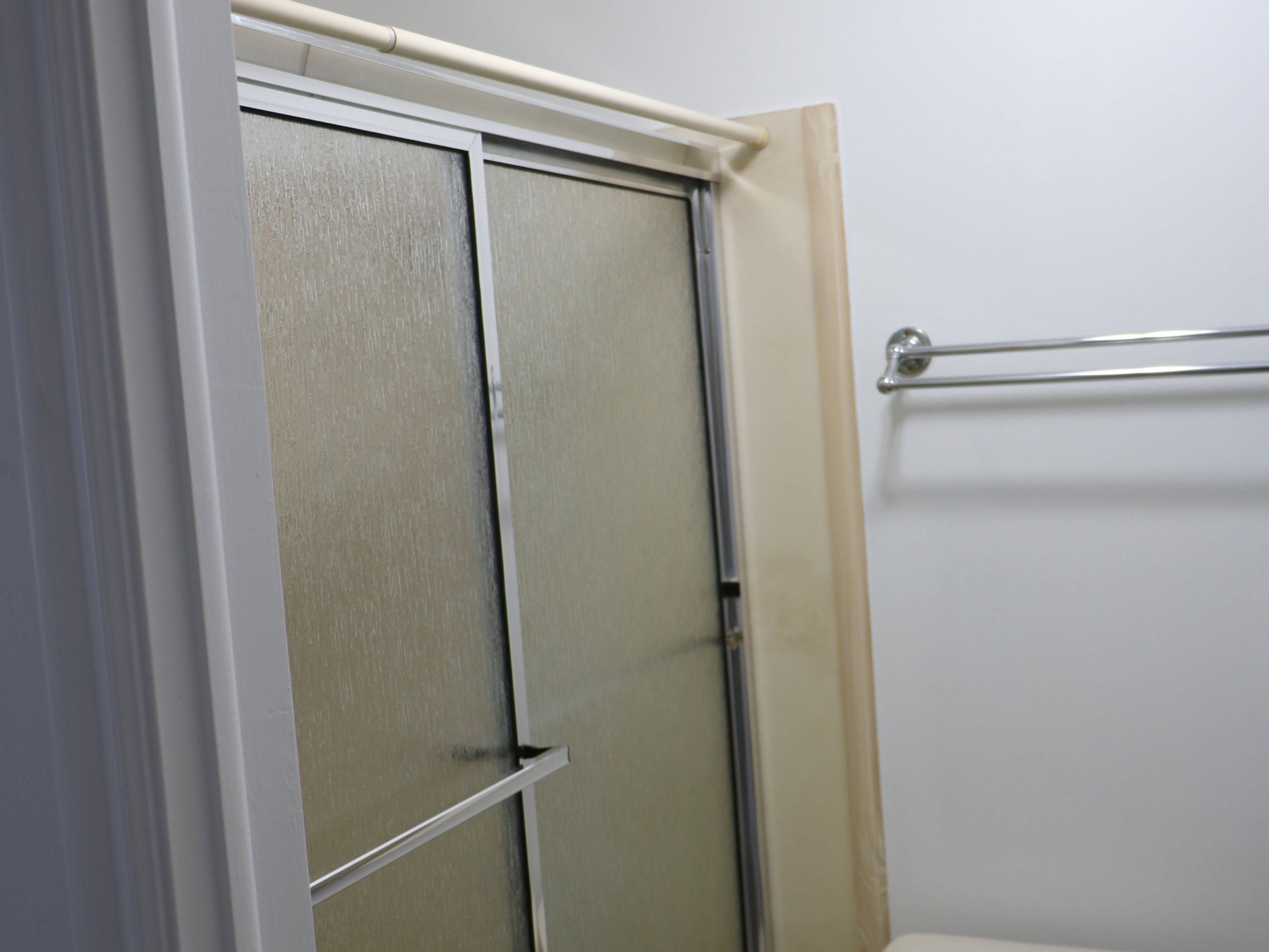 Bathroom featuring a white toilet, chrome towel bar, and a shower enclosure with frosted glass sliding doors