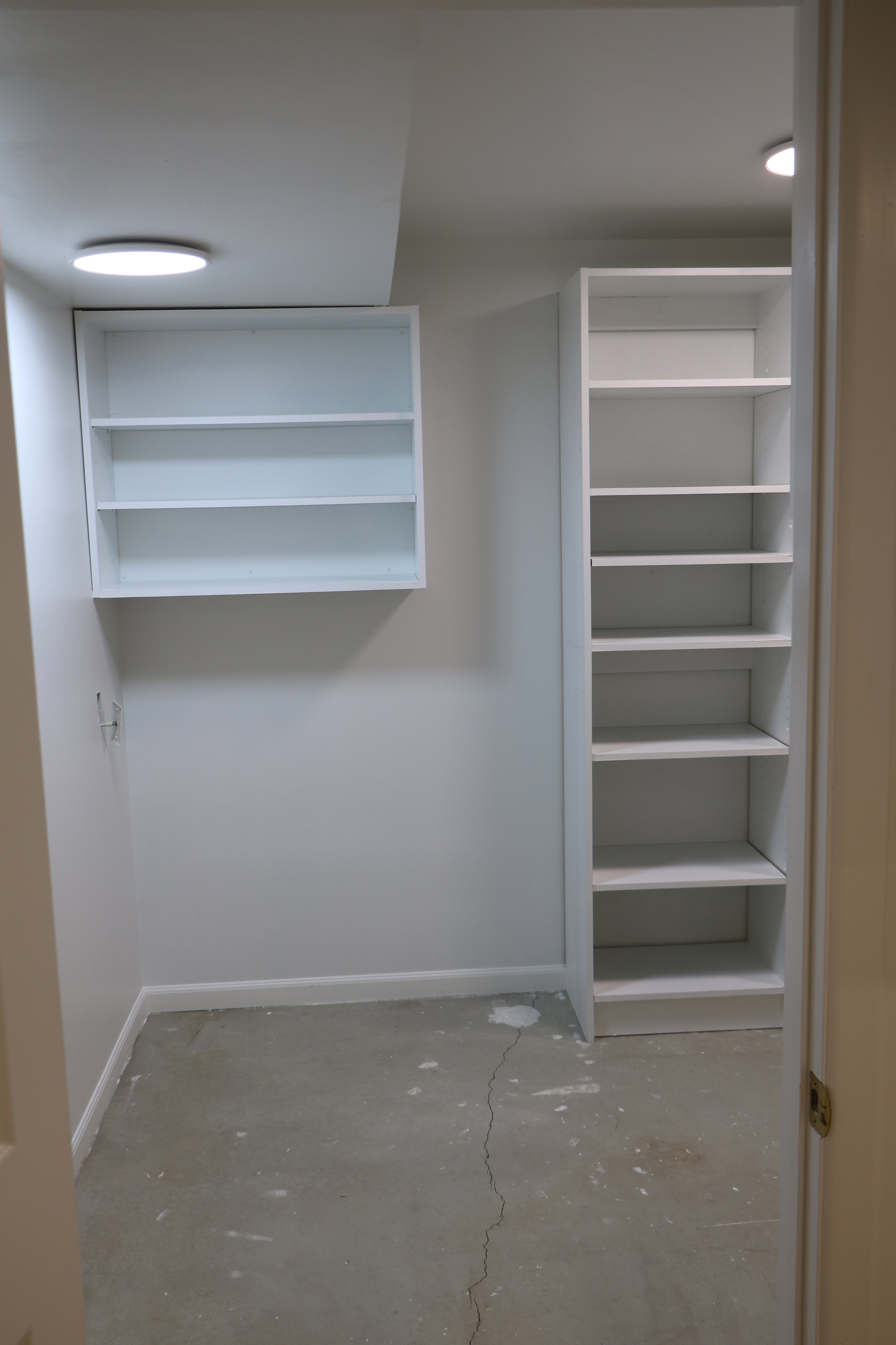 Interior storage space with integrated shelving, built-in wall cabinet, overhead recessed lighting, and painted walls