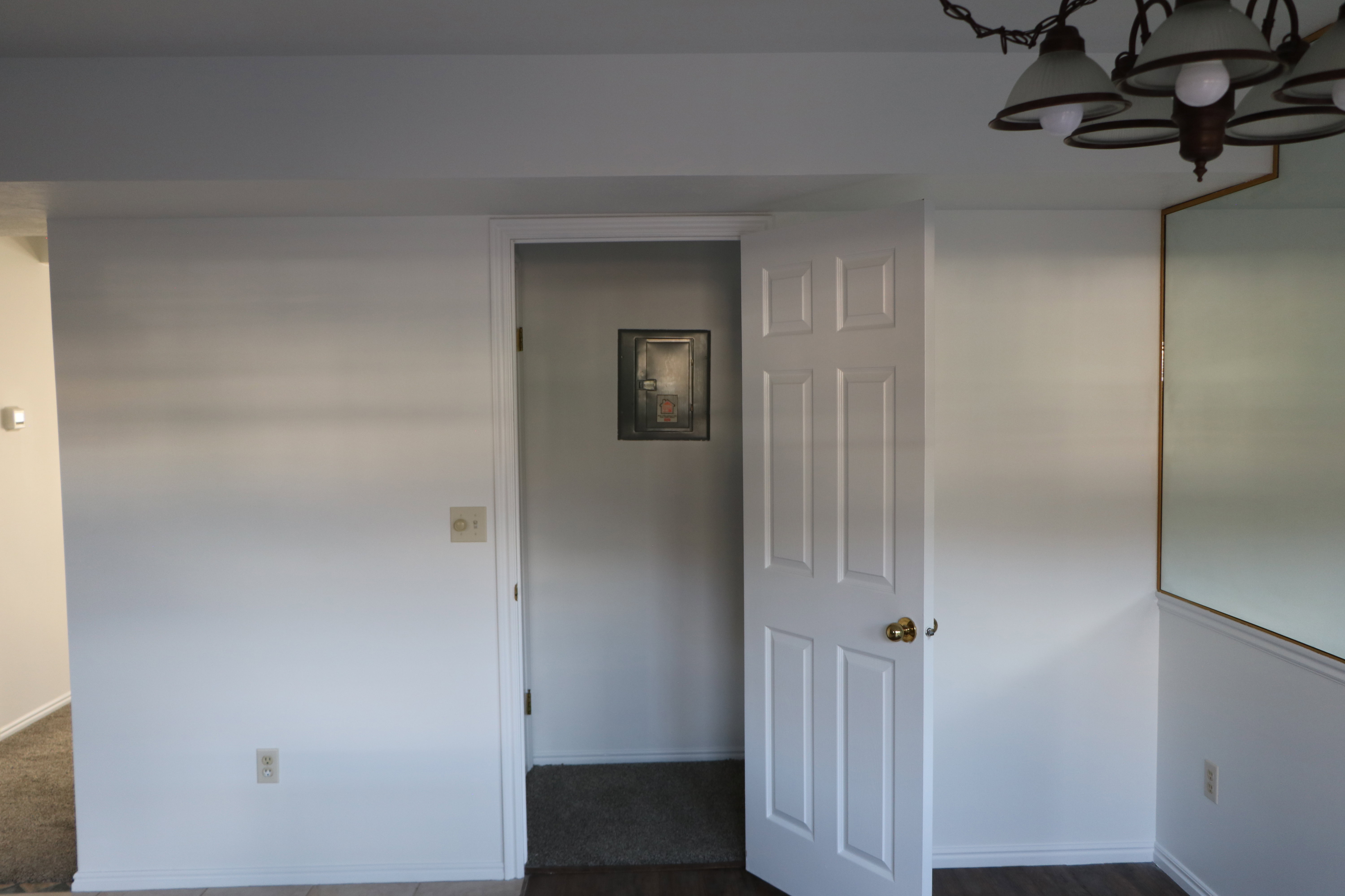 Interior space featuring white walls and a six-panel door with brass hardware