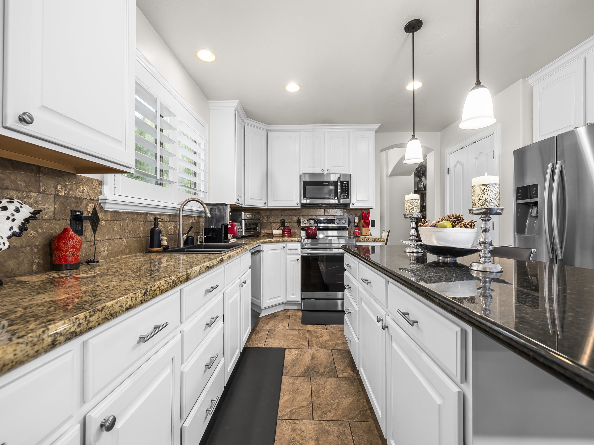 Kitchen featuring white cabinetry, two-tone granite countertops, and stainless steel appliances
