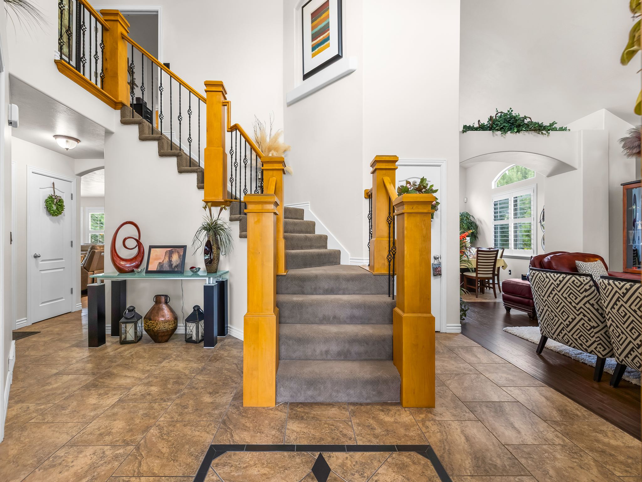 Grand entryway with a sweeping staircase featuring wood balusters and wrought iron spindles