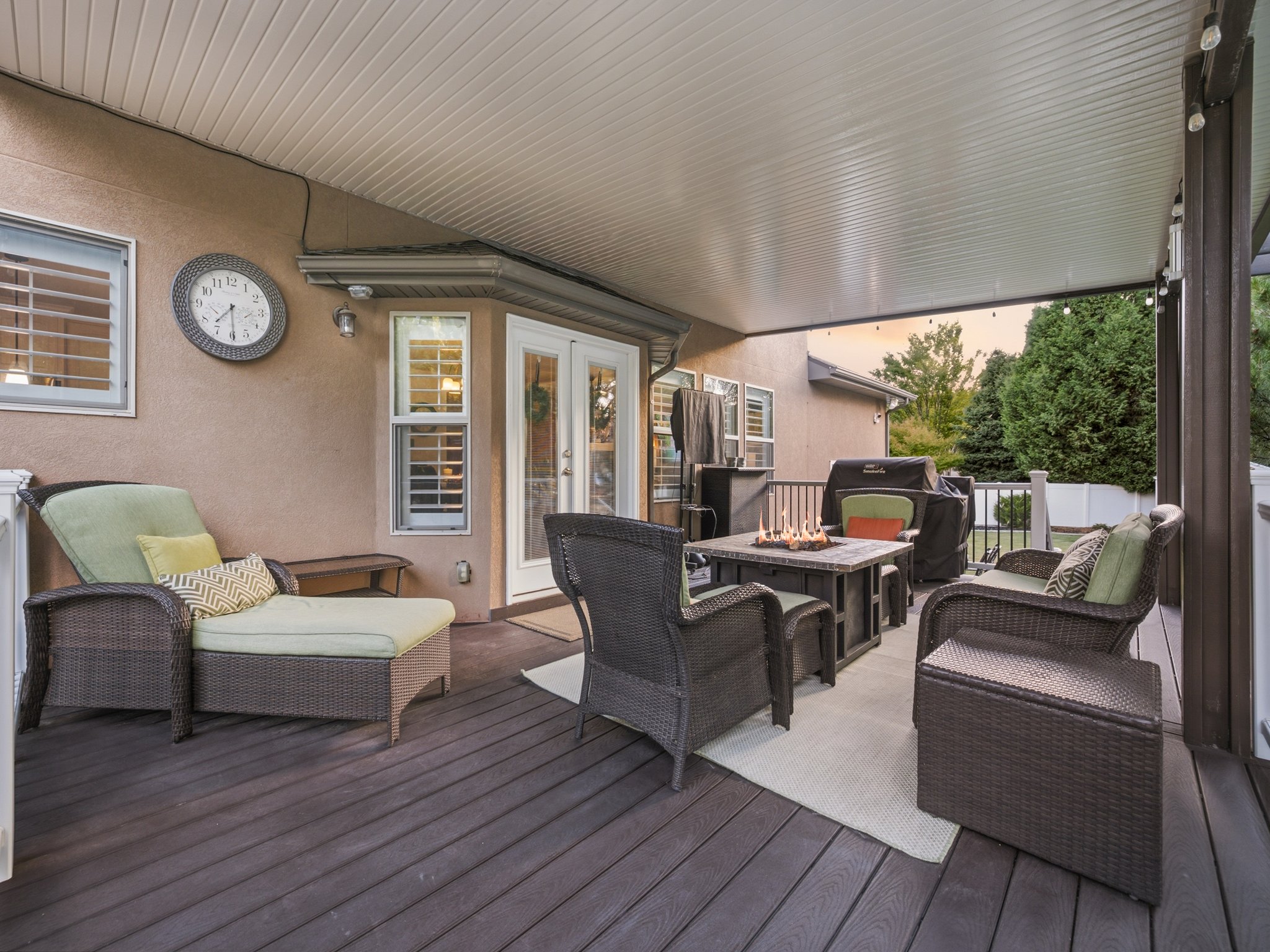 Spacious covered deck featuring a textured ceiling, durable composite decking, and direct access through a double glass door