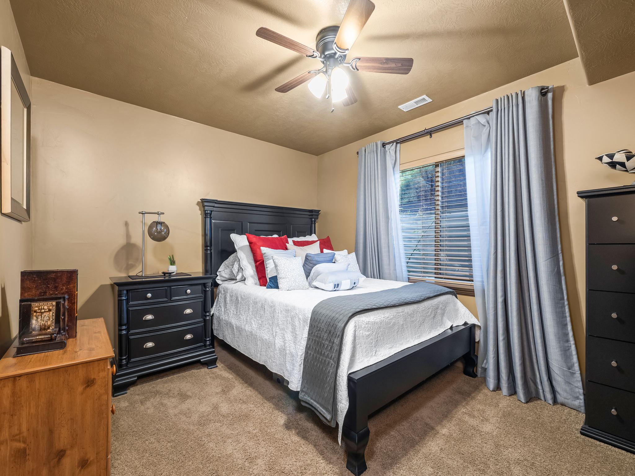 Carpeted room featuring a ceiling fan with integrated lighting, a window with horizontal blinds and drapery rods, and a built-in vent
