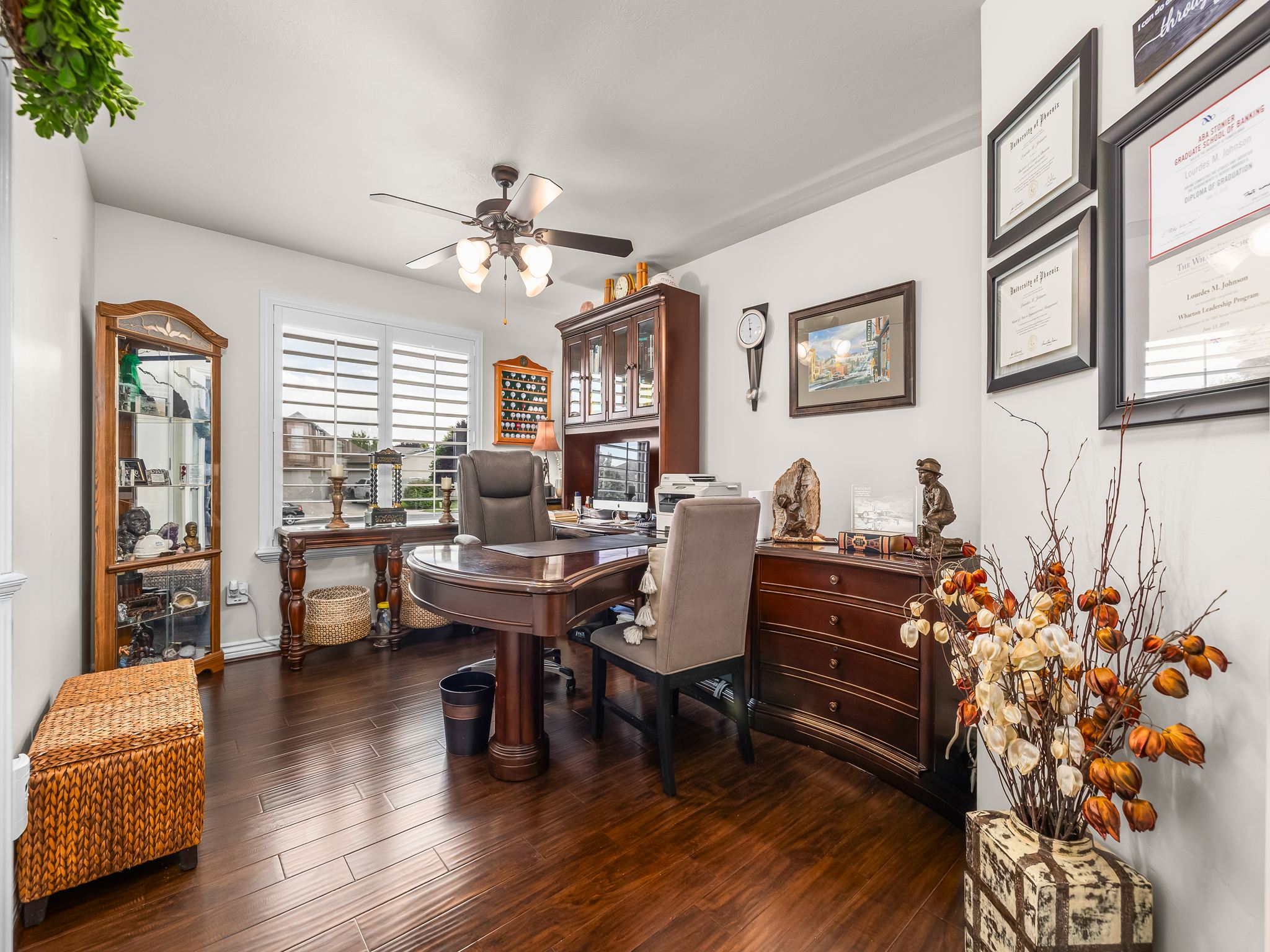 Spacious interior room featuring wood-finish flooring, white walls, and a ceiling fan with integrated lighting