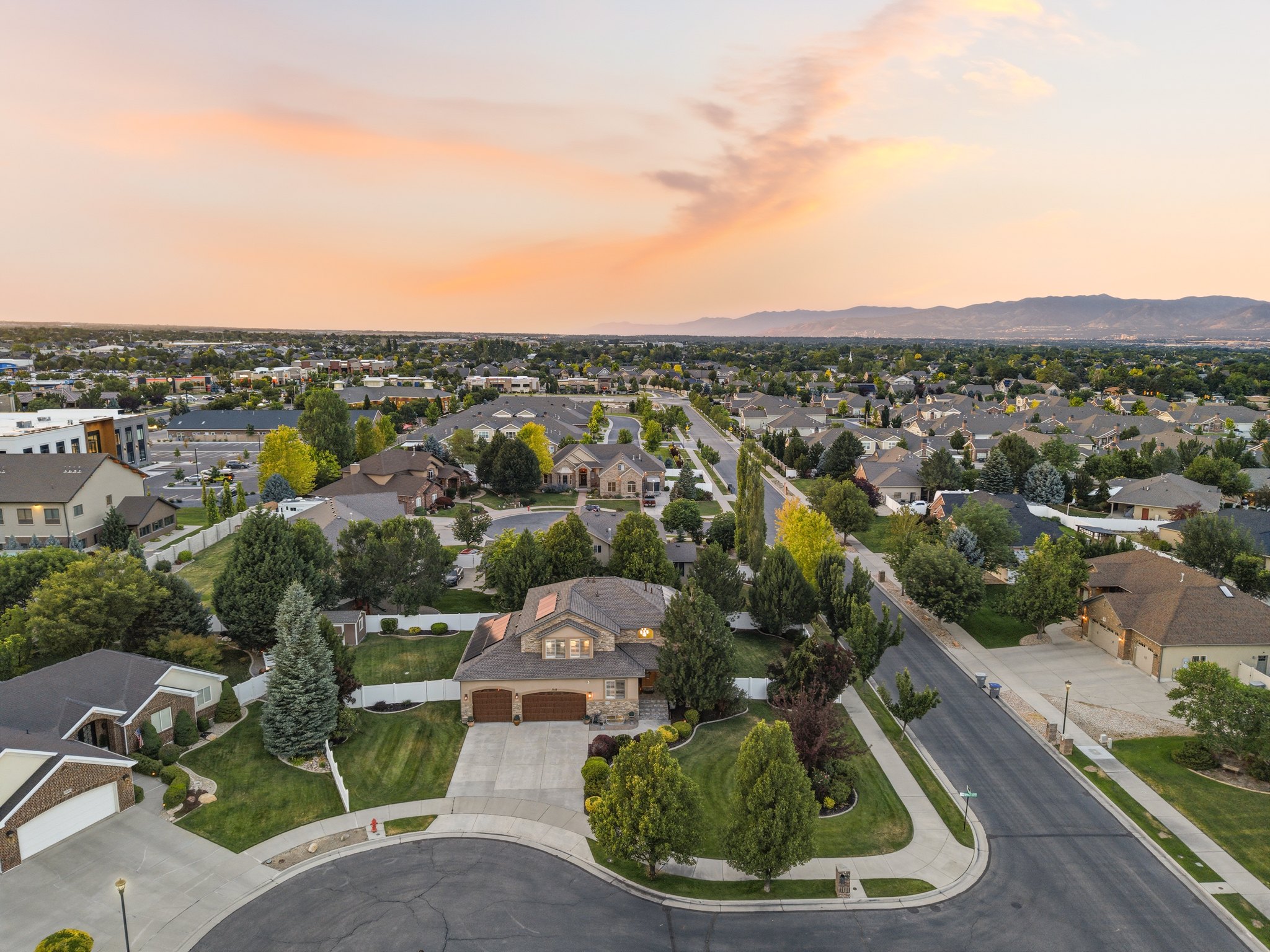 Suburban neighborhood featuring residential properties with mature landscaping, paved streets, and a mountainous backdrop