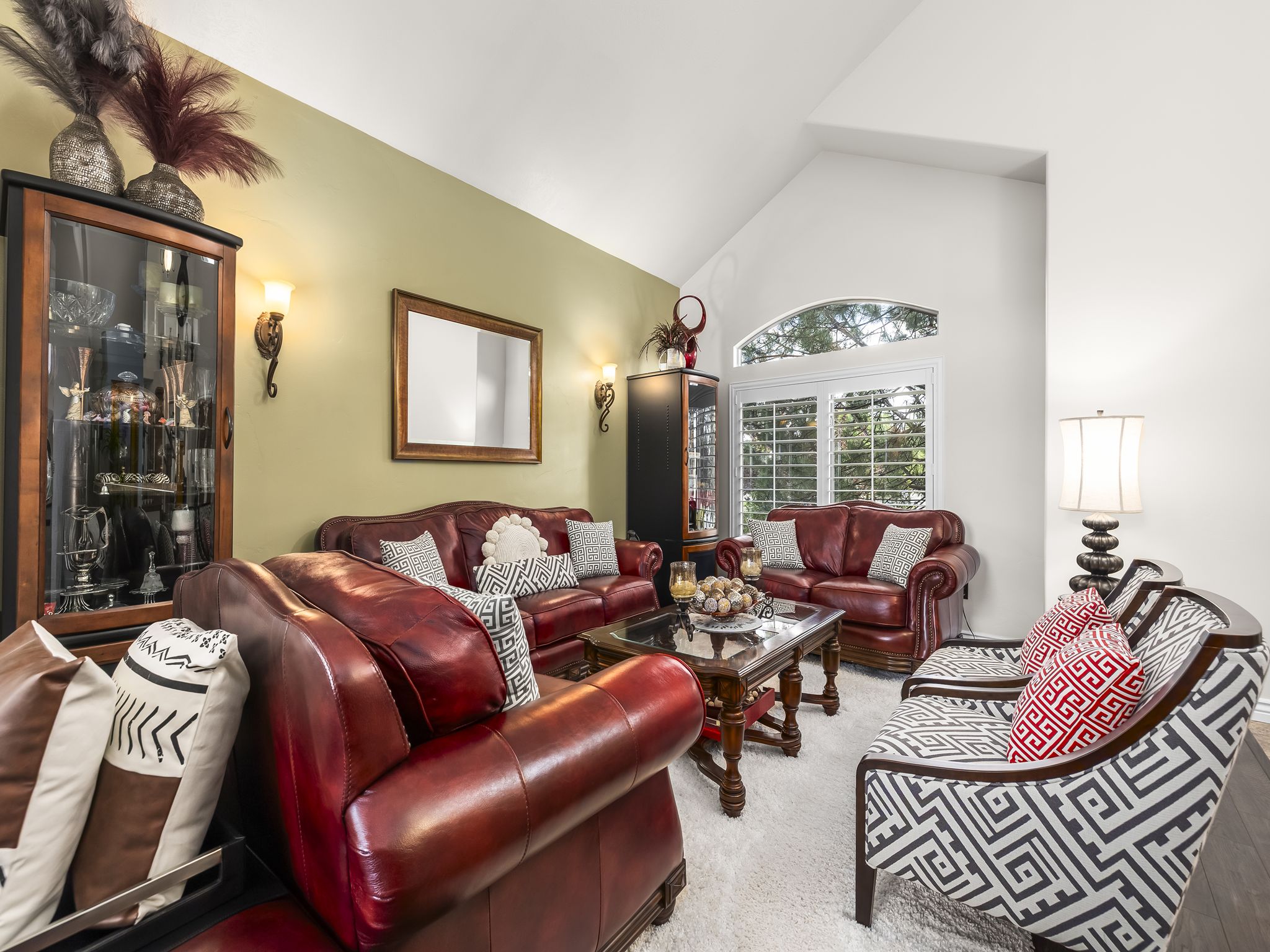 Spacious living area featuring a vaulted ceiling and an arched transom window