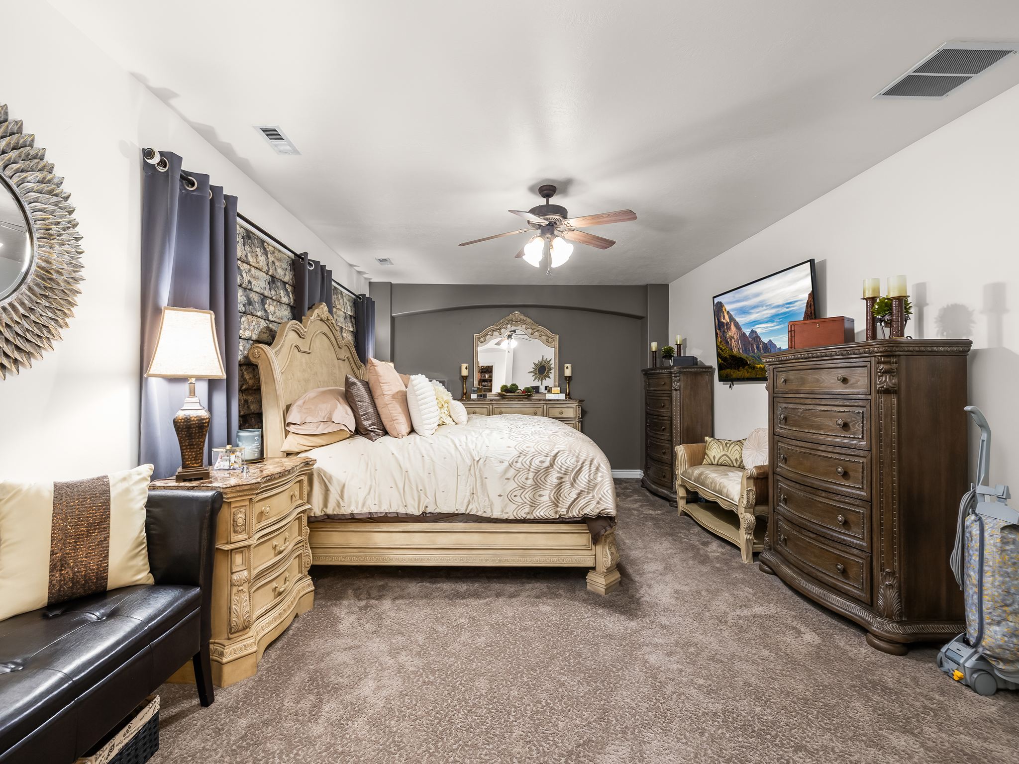 Spacious room featuring neutral carpeting, a ceiling fan with integrated lighting, and a dark accent wall with an arched doorway