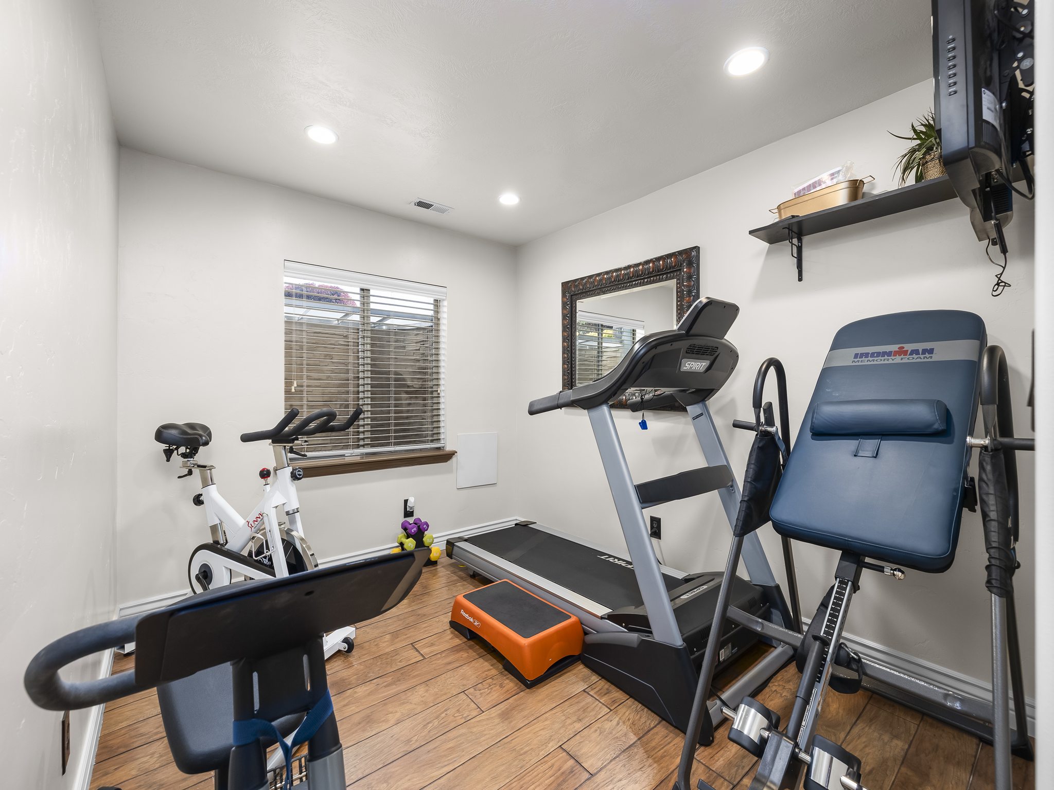 Versatile room featuring wood-finish flooring, recessed lighting, and a window with horizontal blinds