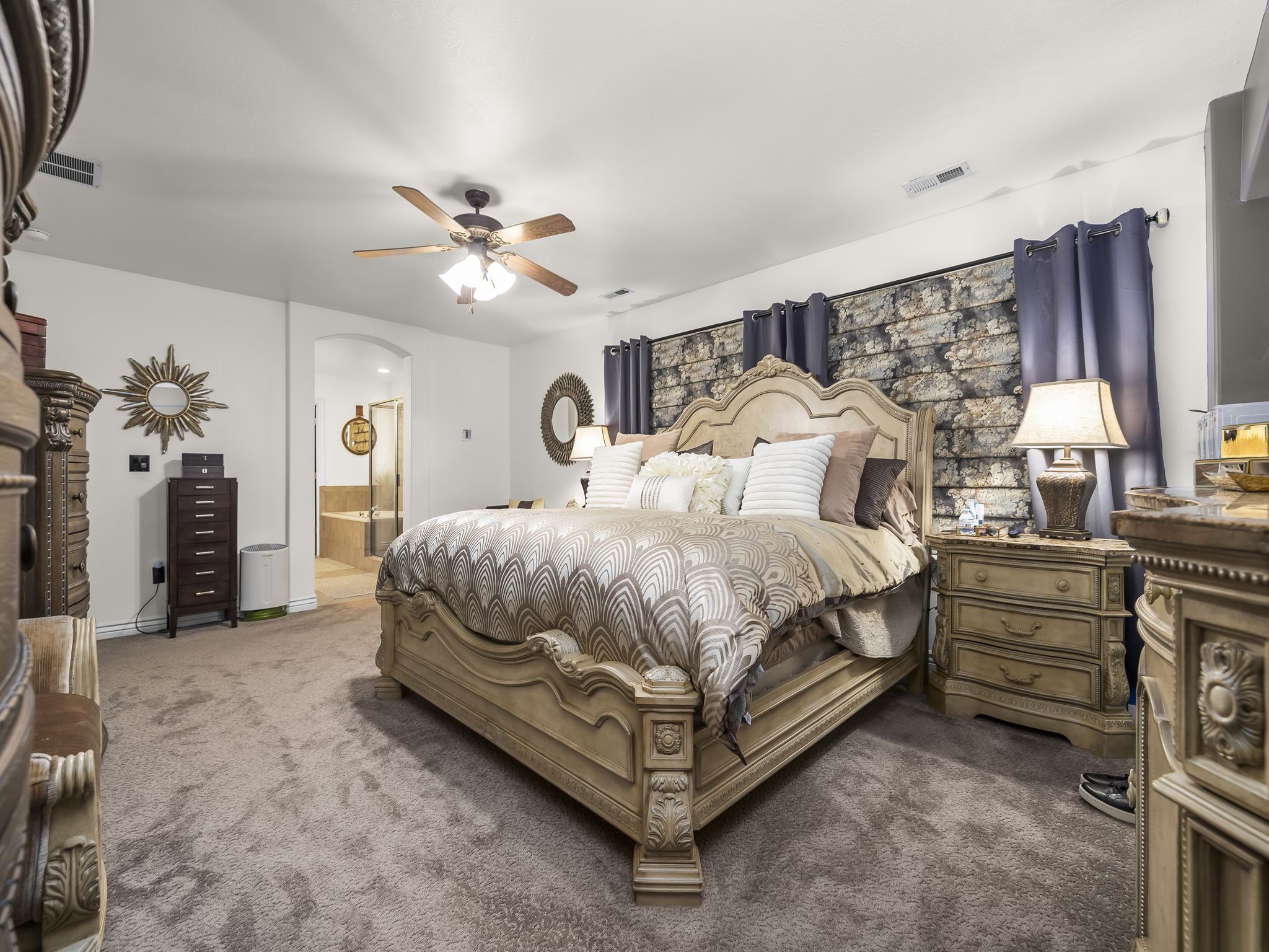 Carpeted sleeping area featuring a ceiling fan, arched doorway, and built-in alcove with a tiled surround