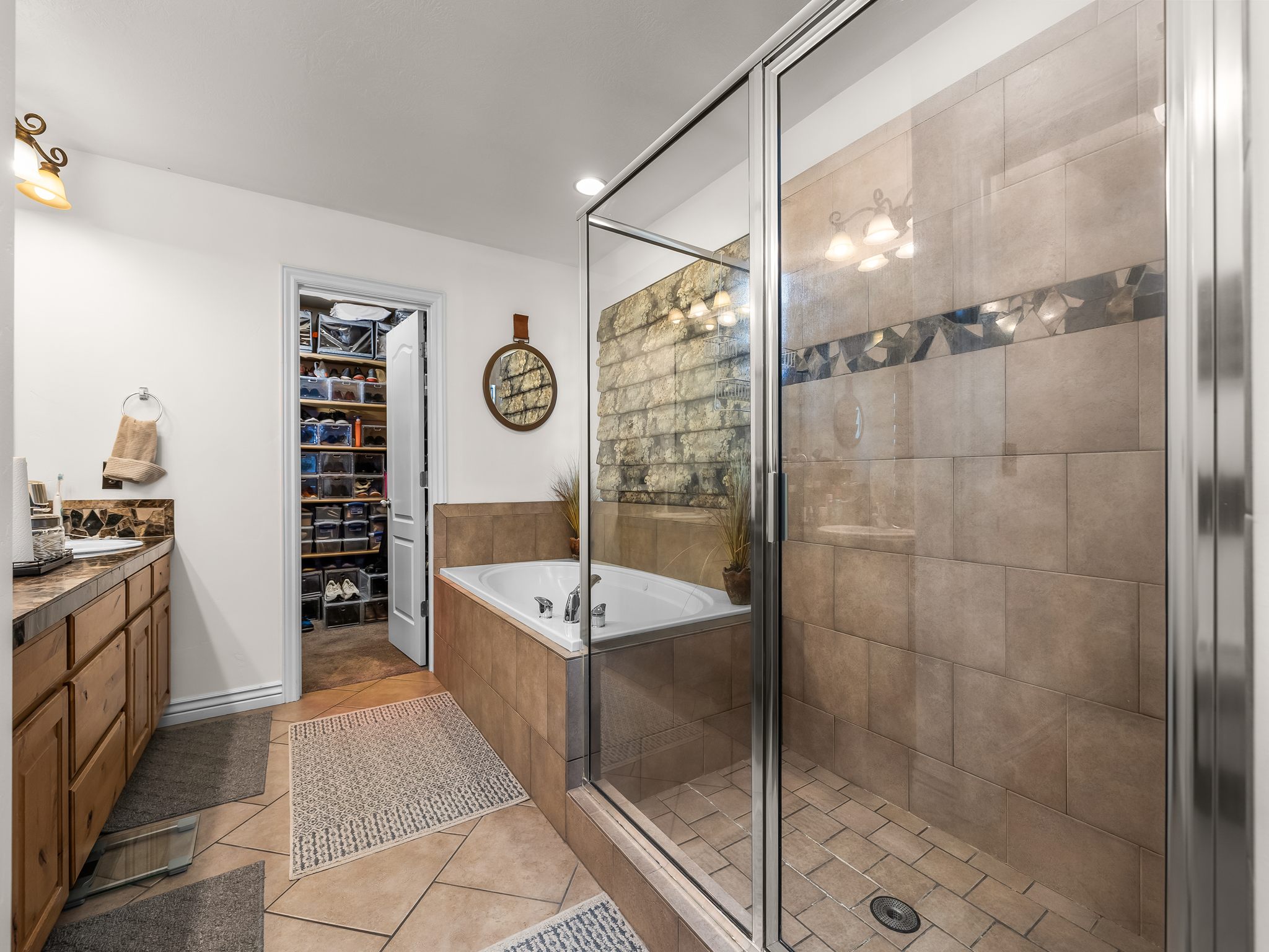 Bathroom featuring a glass-enclosed shower, a built-in jetted tub, and a vanity with a countertop and wood-finish cabinetry