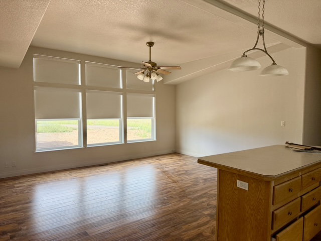 Open-concept living area featuring wood-finish flooring, a vaulted ceiling, and a multi-pane window array
