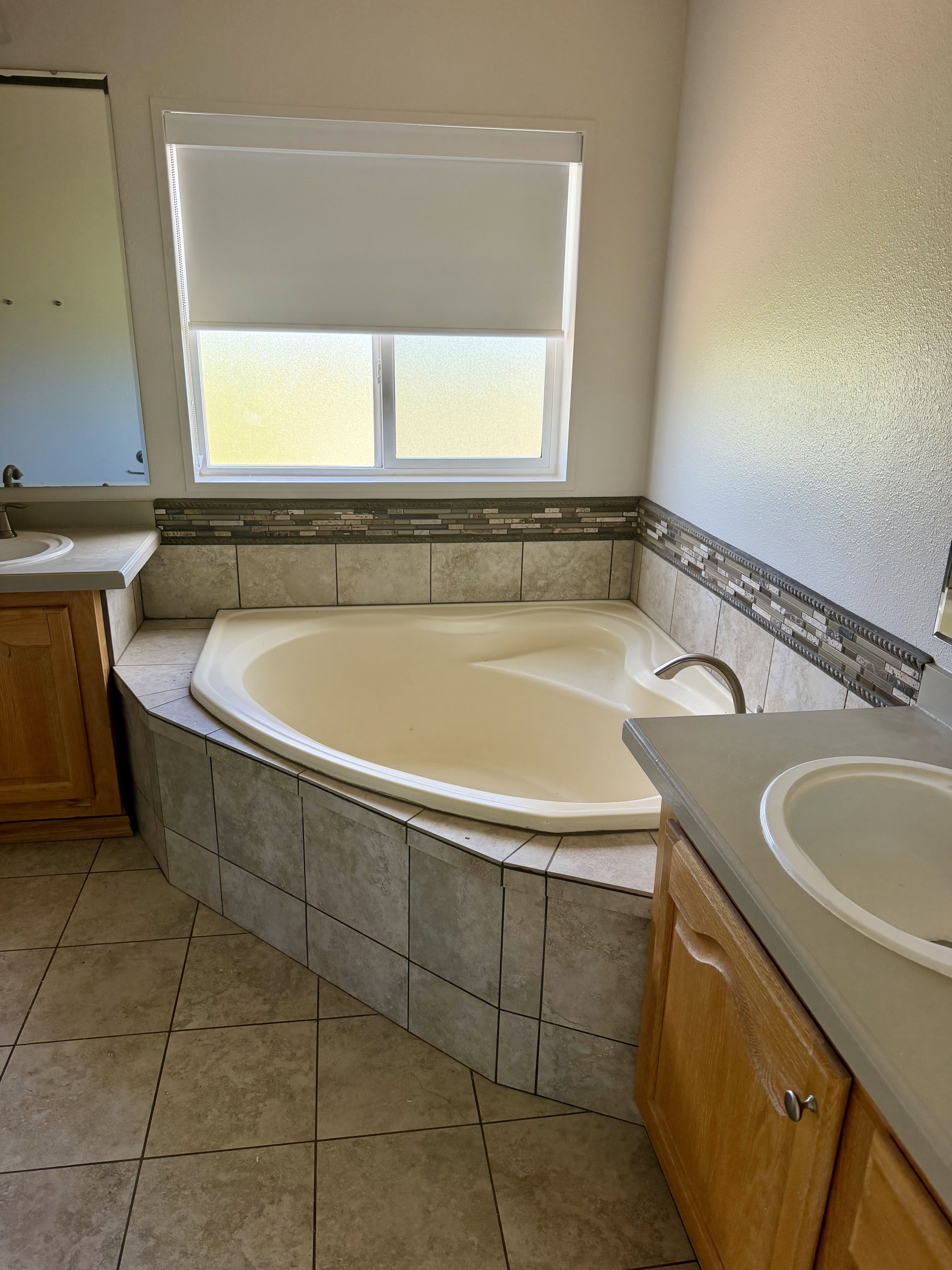 Built-in soaking tub with tile surround, complemented by a mosaic tile accent strip