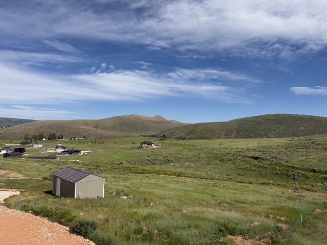 Expansive rural landscape featuring rolling hills and distant residential structures
