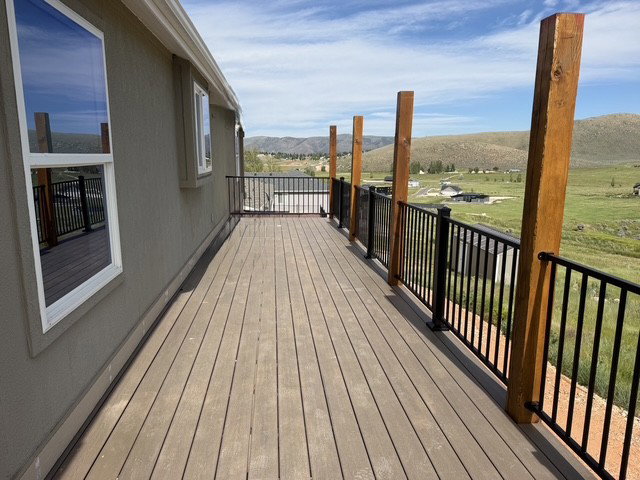 Expansive exterior deck featuring composite decking, black metal railings, and natural wood posts