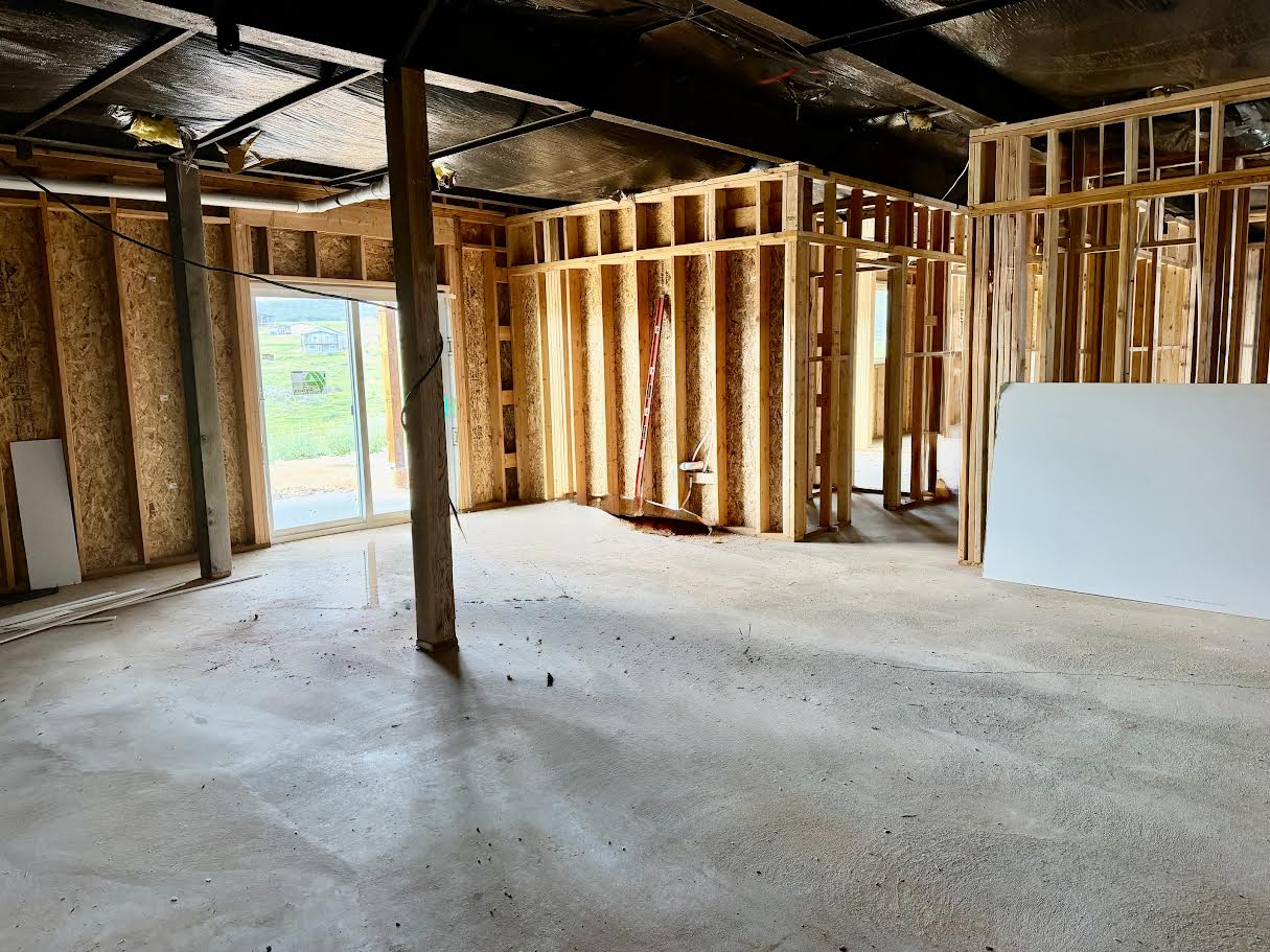 Unfinished lower level featuring wood framing, exposed concrete flooring, and a sliding glass door