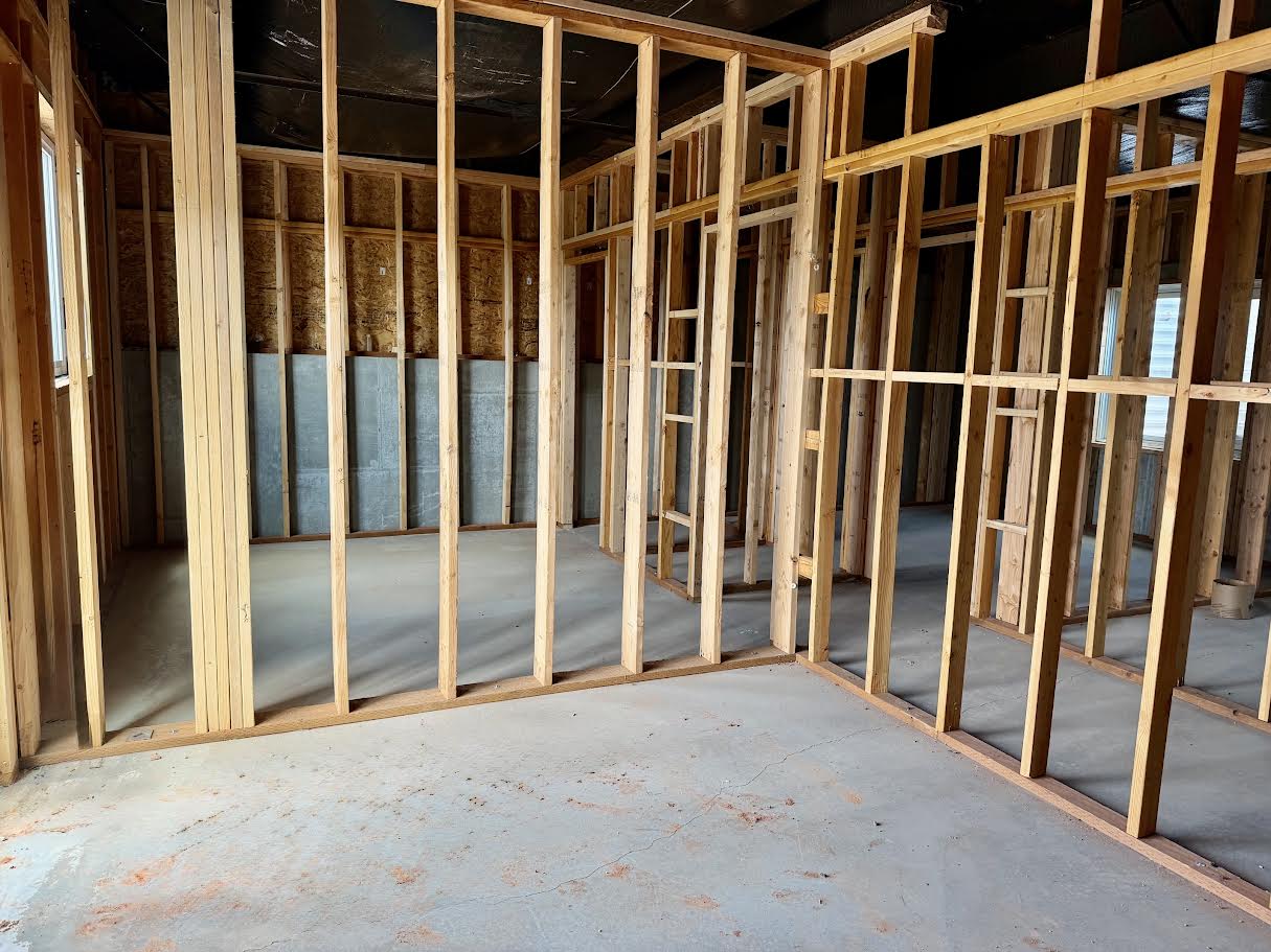 Unfinished interior space featuring wood framing, concrete flooring, and exposed insulation