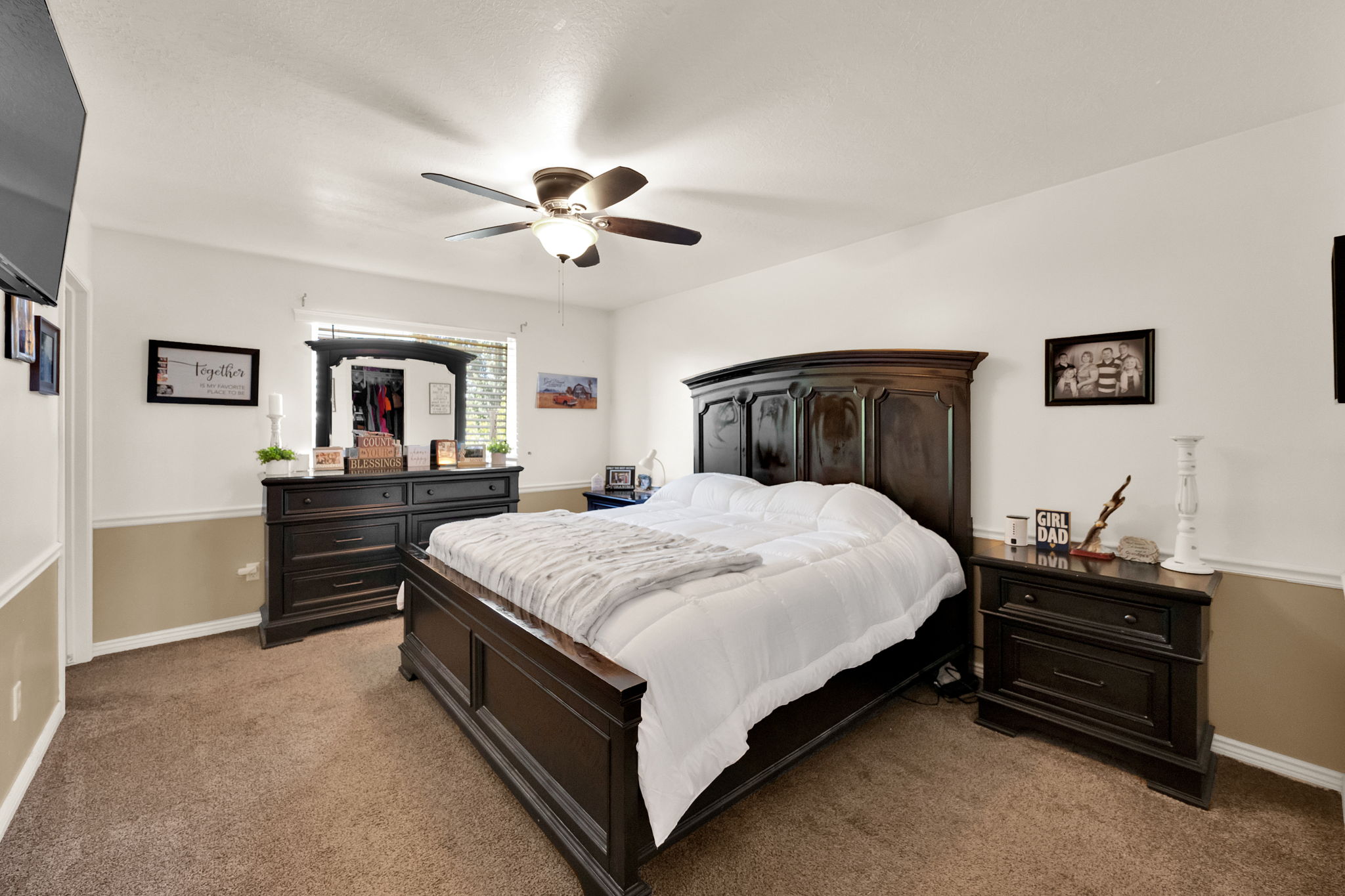 Carpeted bedroom featuring a ceiling fan with integrated lighting, a window with horizontal blinds, and two-tone wall finishes