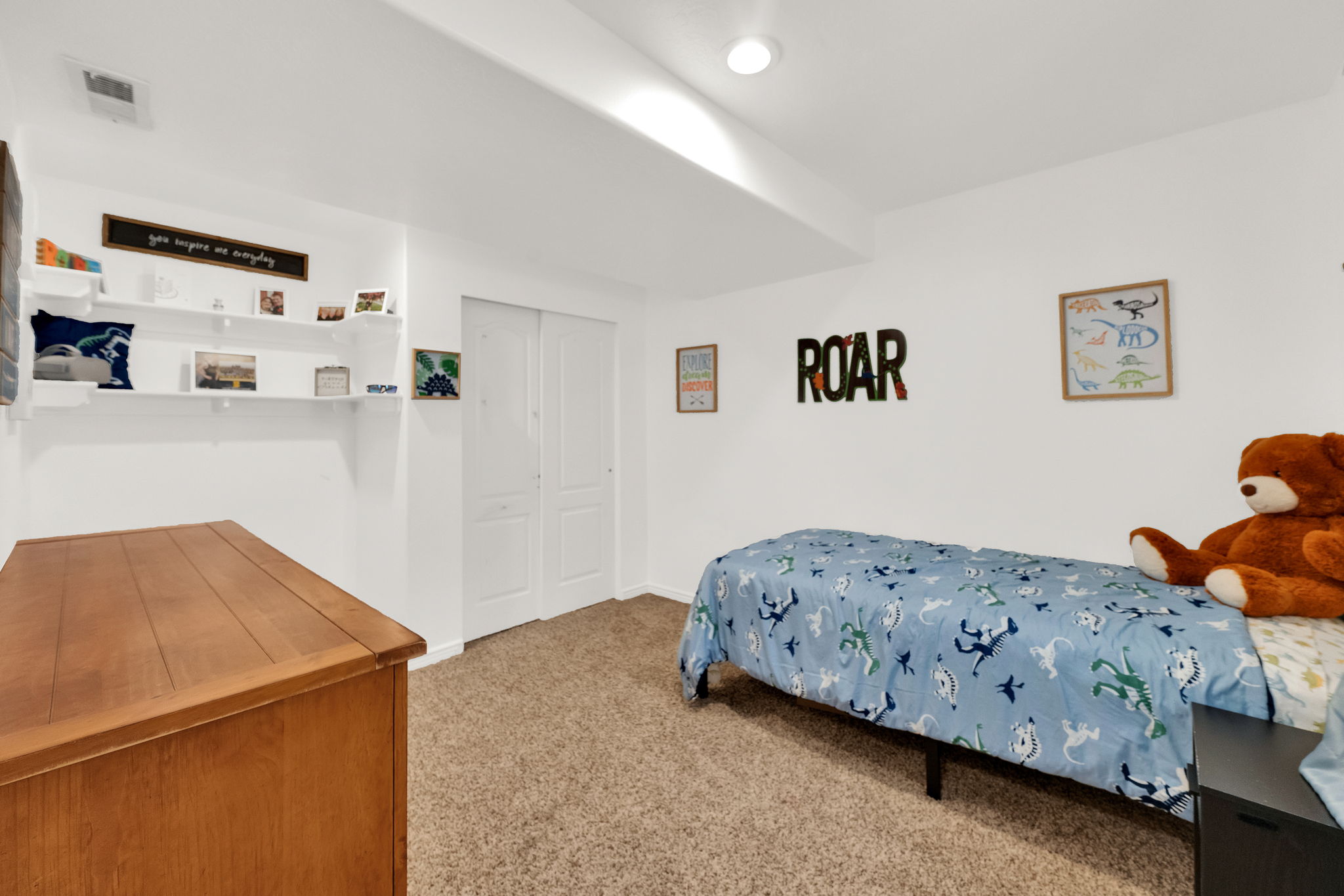 Bright white walls featuring built-in shelving, soft carpet flooring, and a flush-mount ceiling light