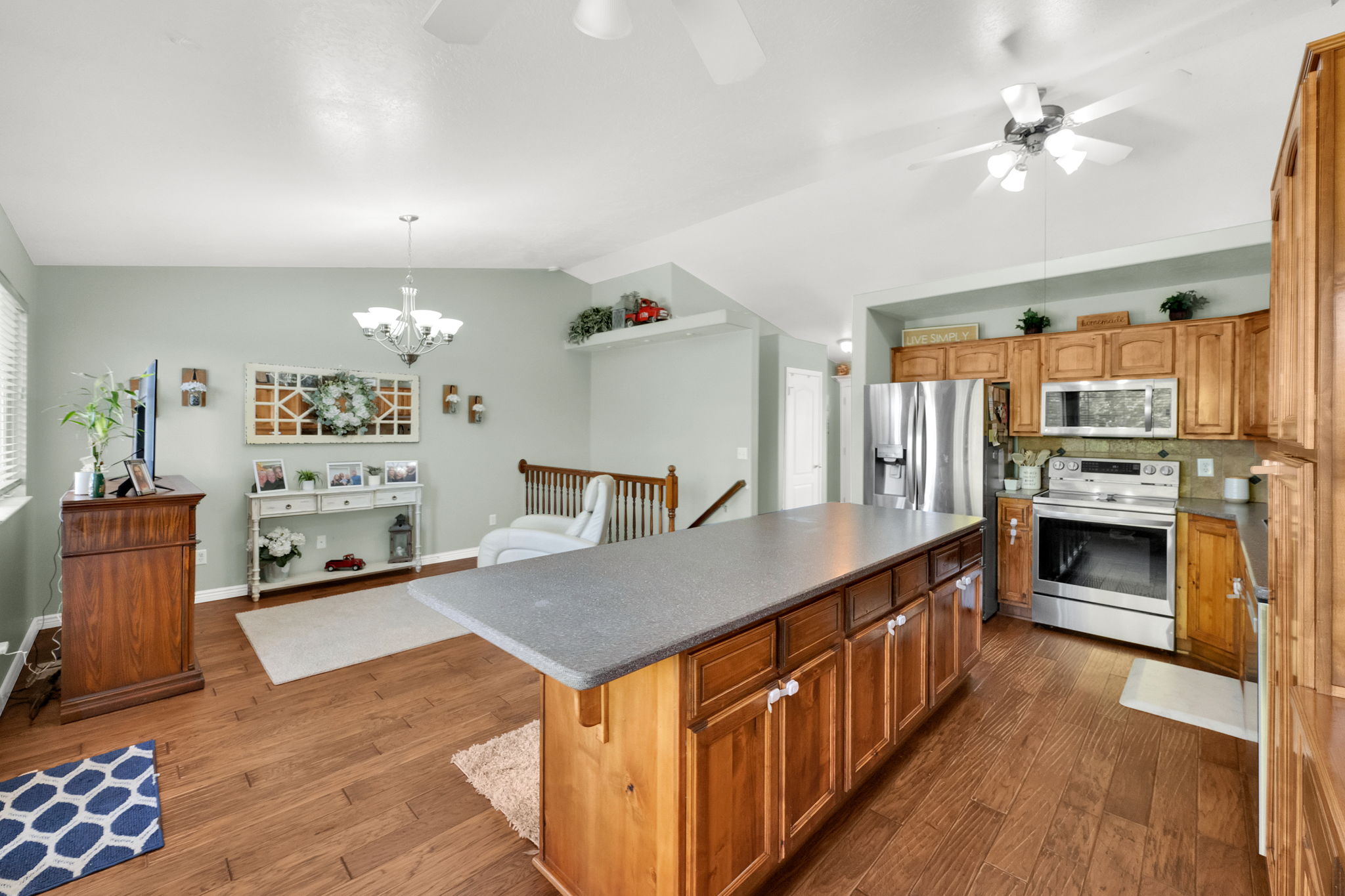 Spacious kitchen island with a dark countertop, wood-finish flooring, recessed lighting, and stainless steel appliances
