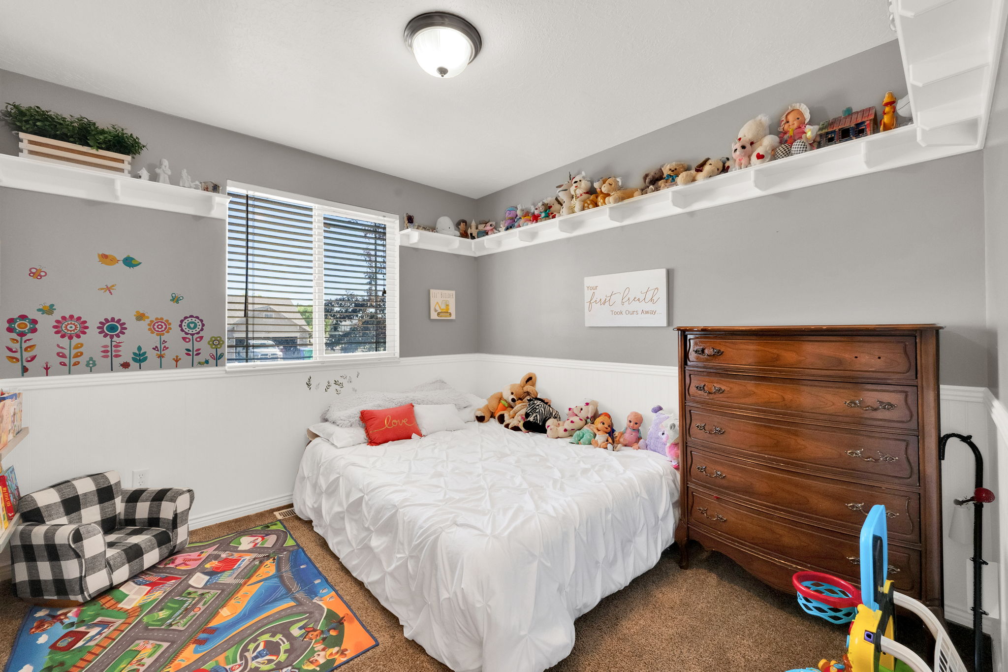 Carpeted room featuring a window with blinds, white shelving around the perimeter, a white chair rail, and a semi-flush mount ceiling light fixture