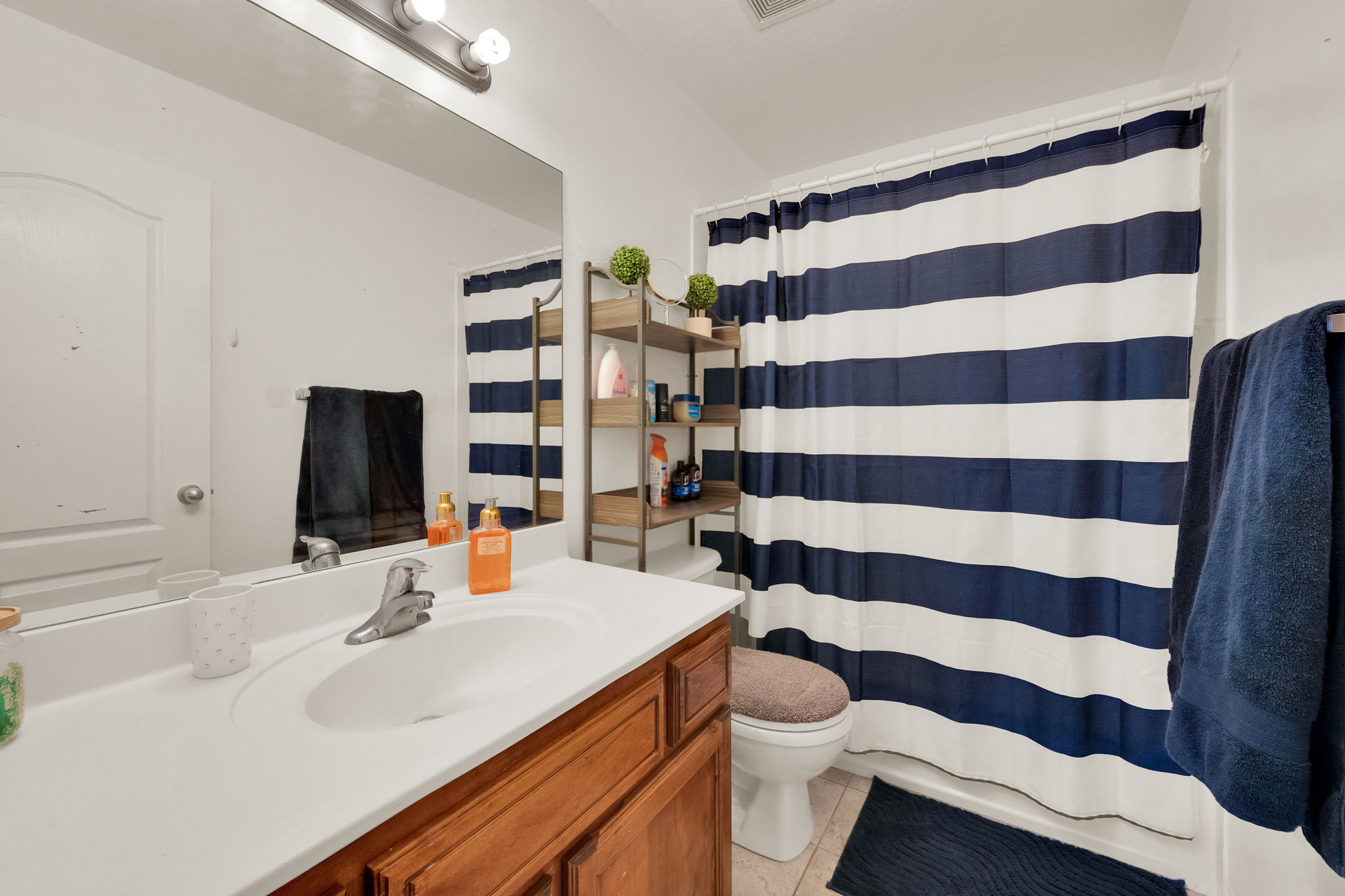 Full bathroom featuring a wood-finish vanity with an integrated sink, polished chrome faucet, and a large wall-mounted mirror
