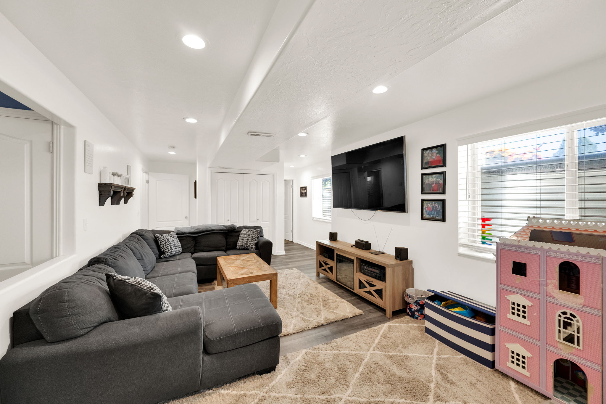 Spacious living area featuring recessed lighting, durable wood-finish flooring, and white window blinds