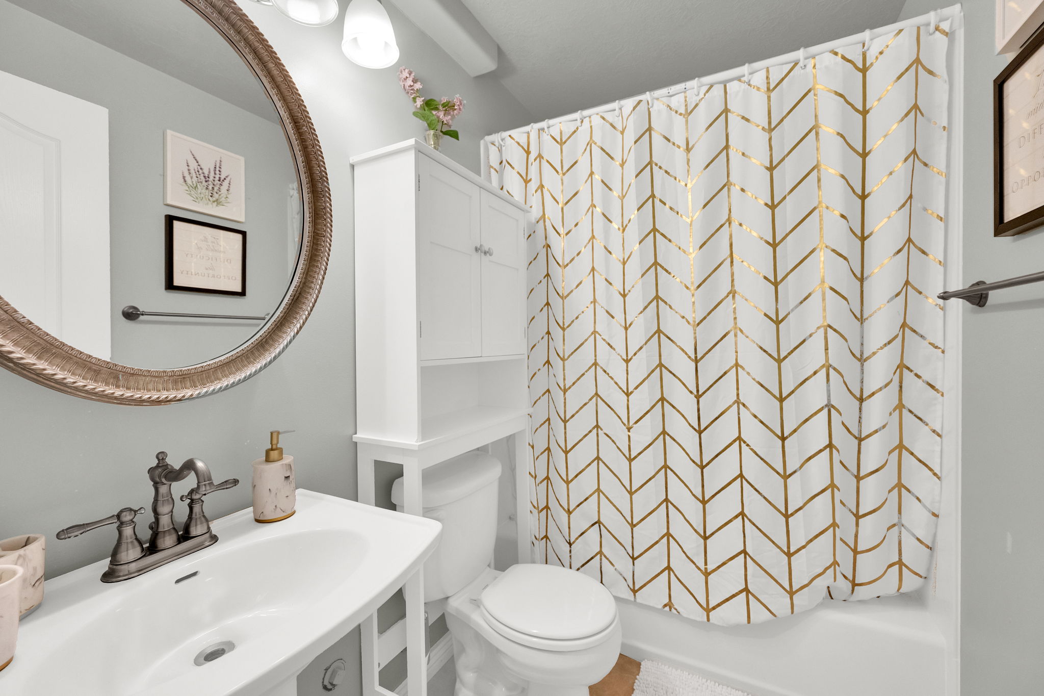 Bathroom featuring a white vanity with integrated sink, bronze-finish faucet, and a large round mirror
