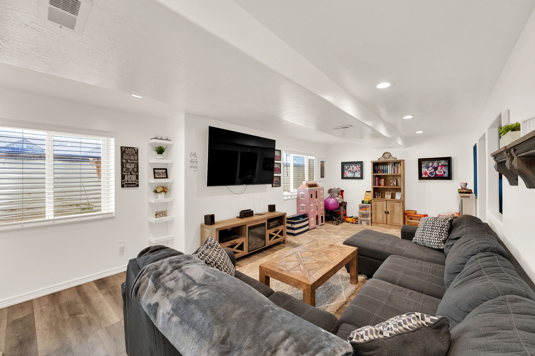 Spacious lower-level living area featuring recessed lighting, a corner shelving unit, and multiple windows