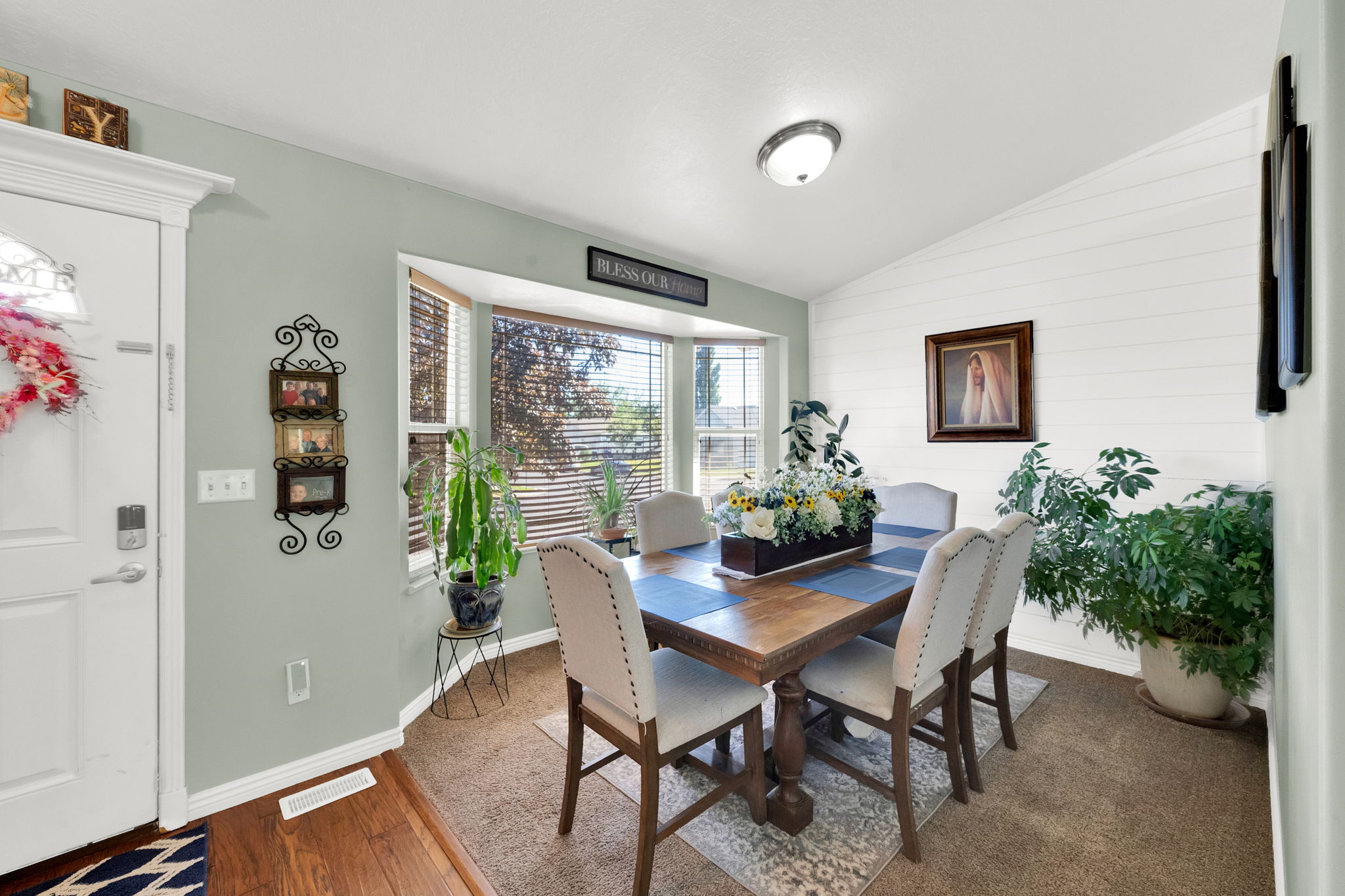 Dining area featuring a bay window with blinds, a wood-finish dining table, and a white shiplap accent wall