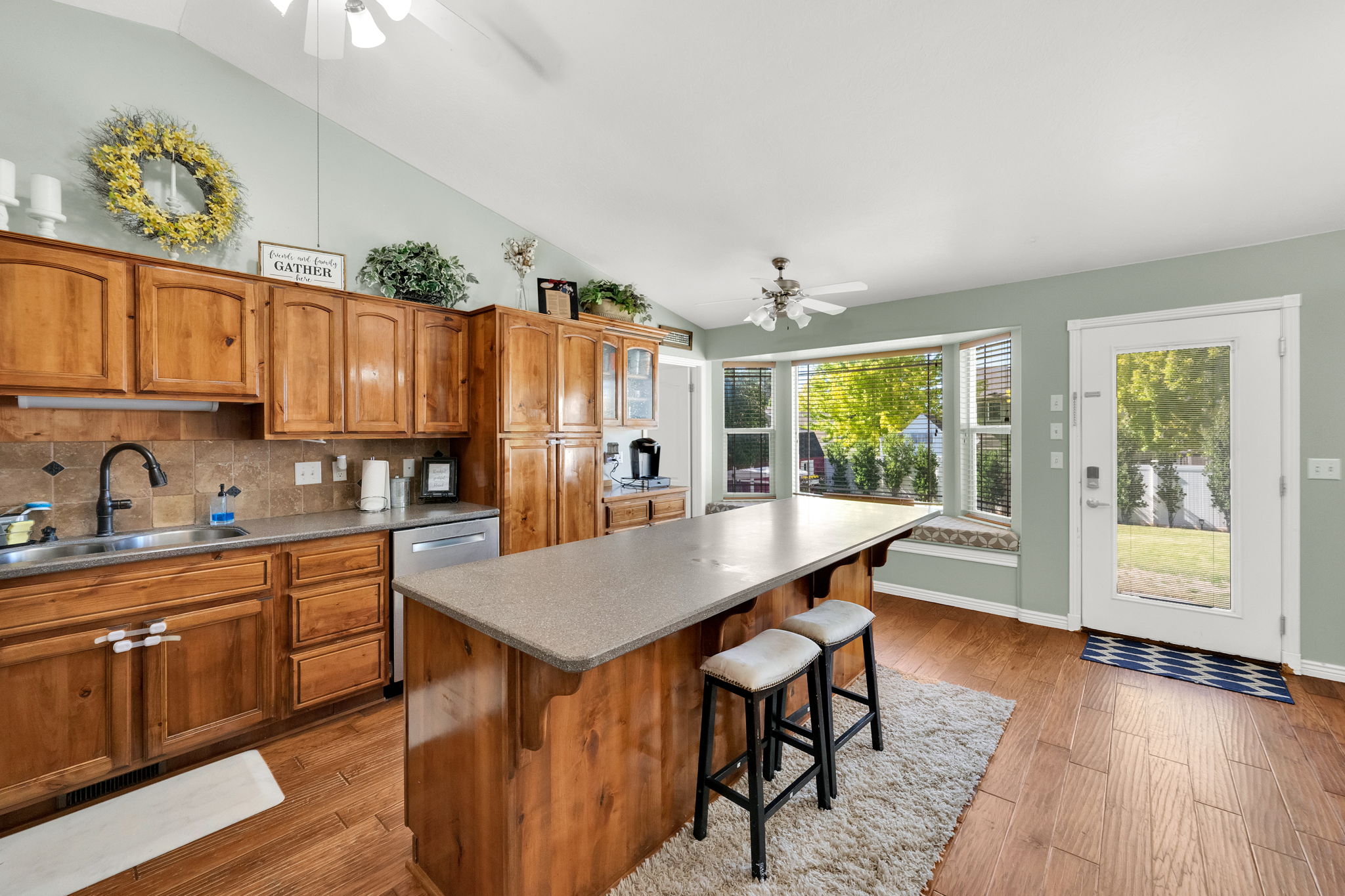 Kitchen featuring wood cabinetry, stone-look countertops, and an integrated island with breakfast bar seating