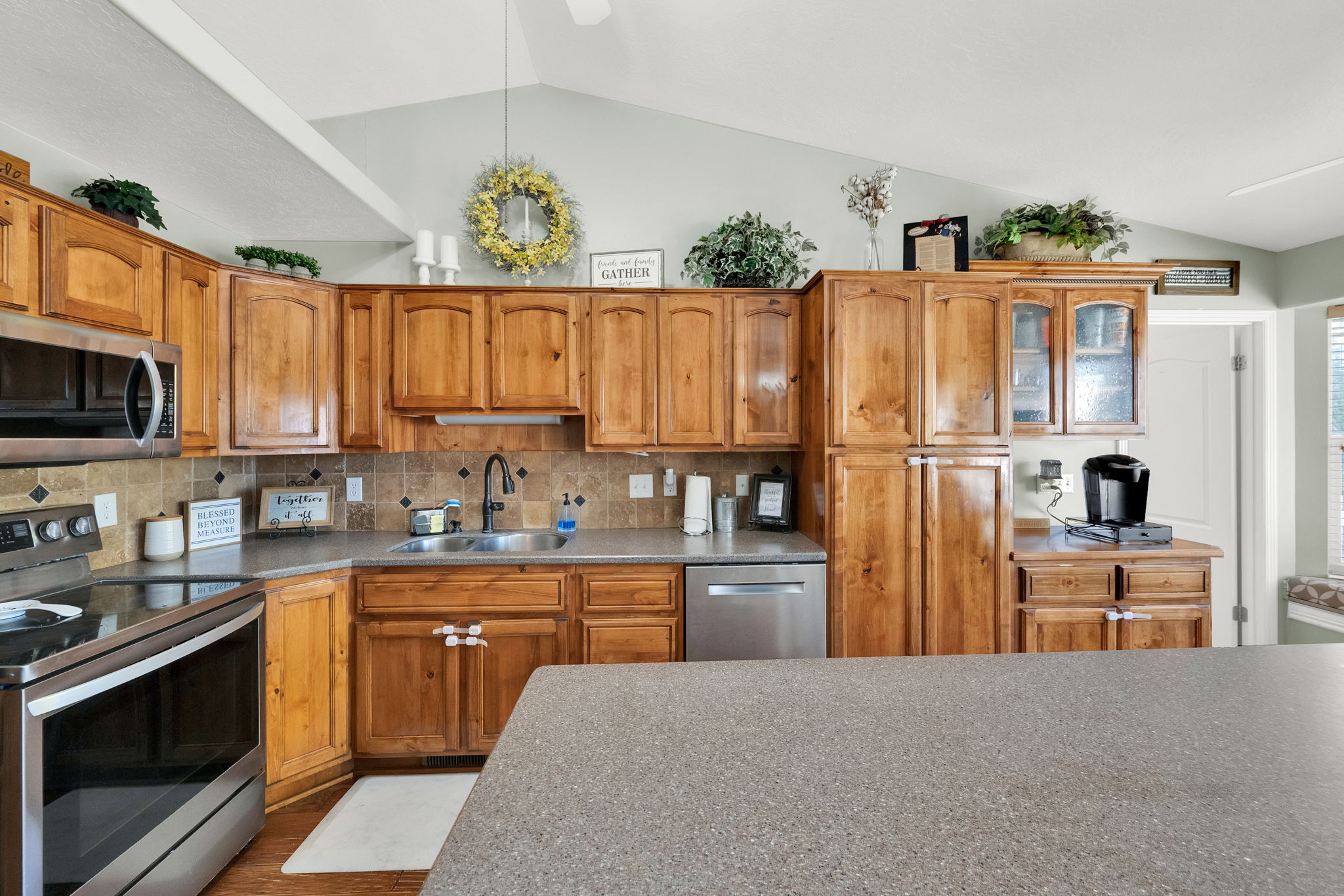 Kitchen featuring wood cabinetry, stainless steel appliances, a tile backsplash, and a large central island with a solid surface countertop