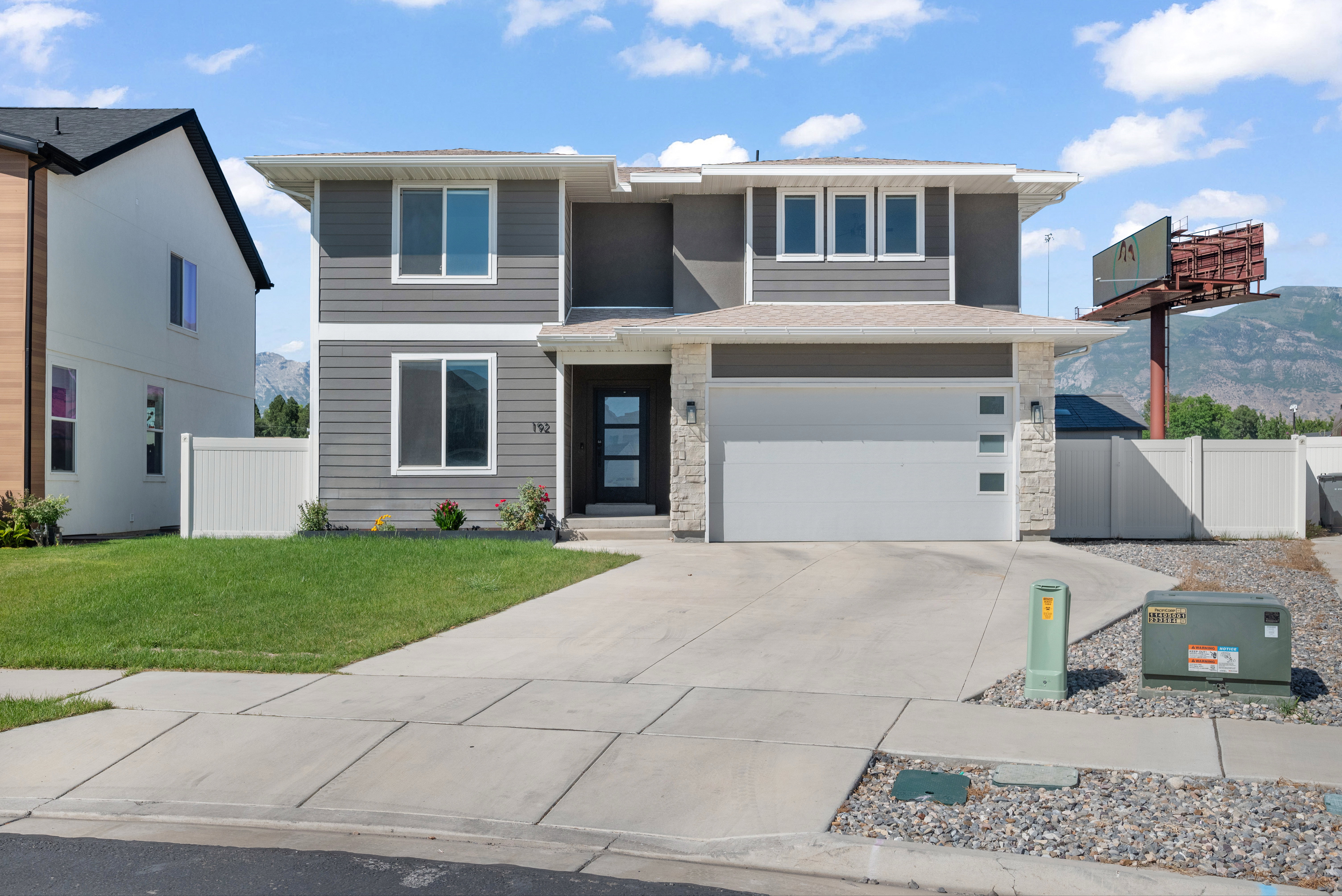 Contemporary two-story residence featuring a gray and white exterior with stone accents