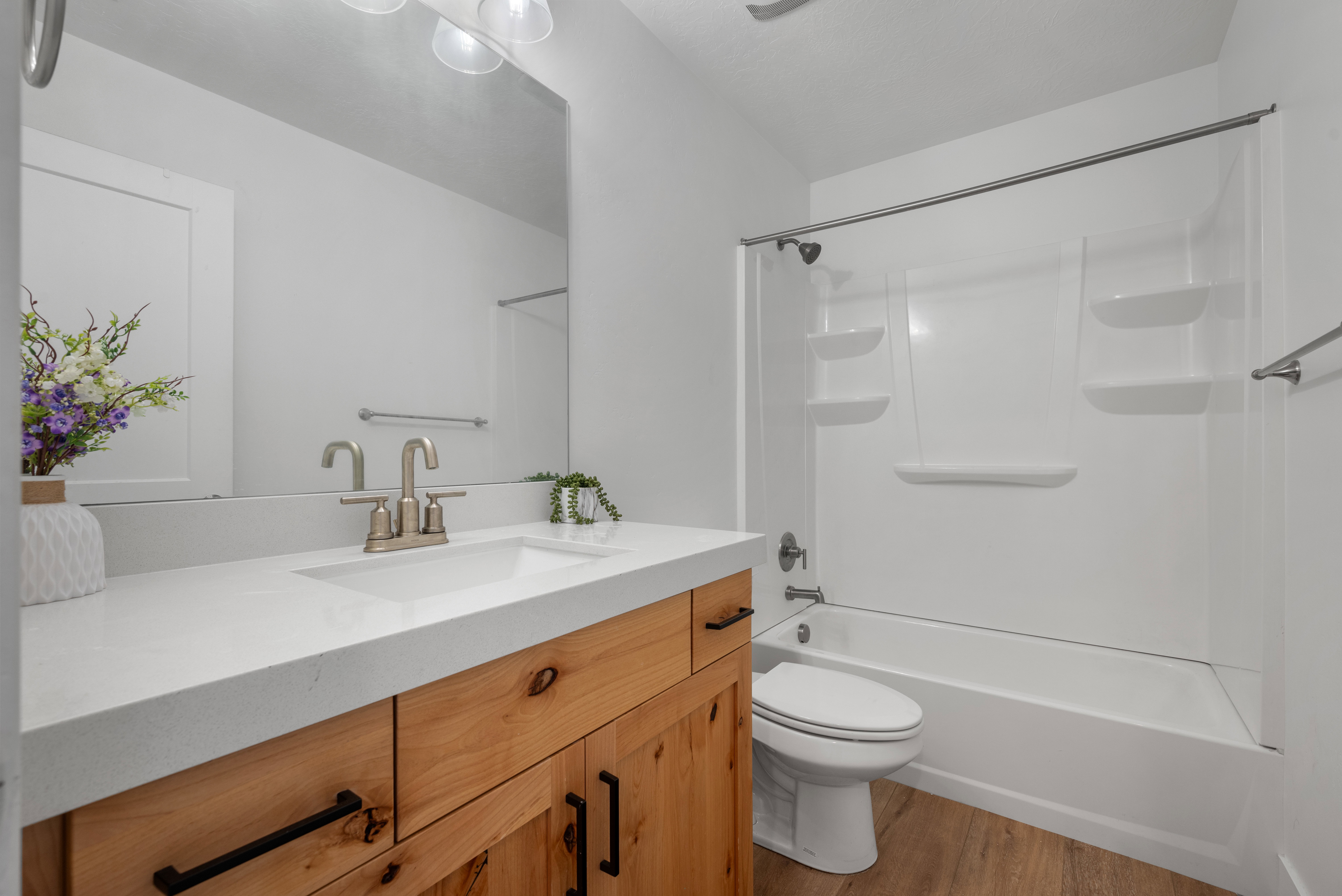 Bathroom featuring a light wood-finish vanity with black hardware, white countertop, and integrated sink