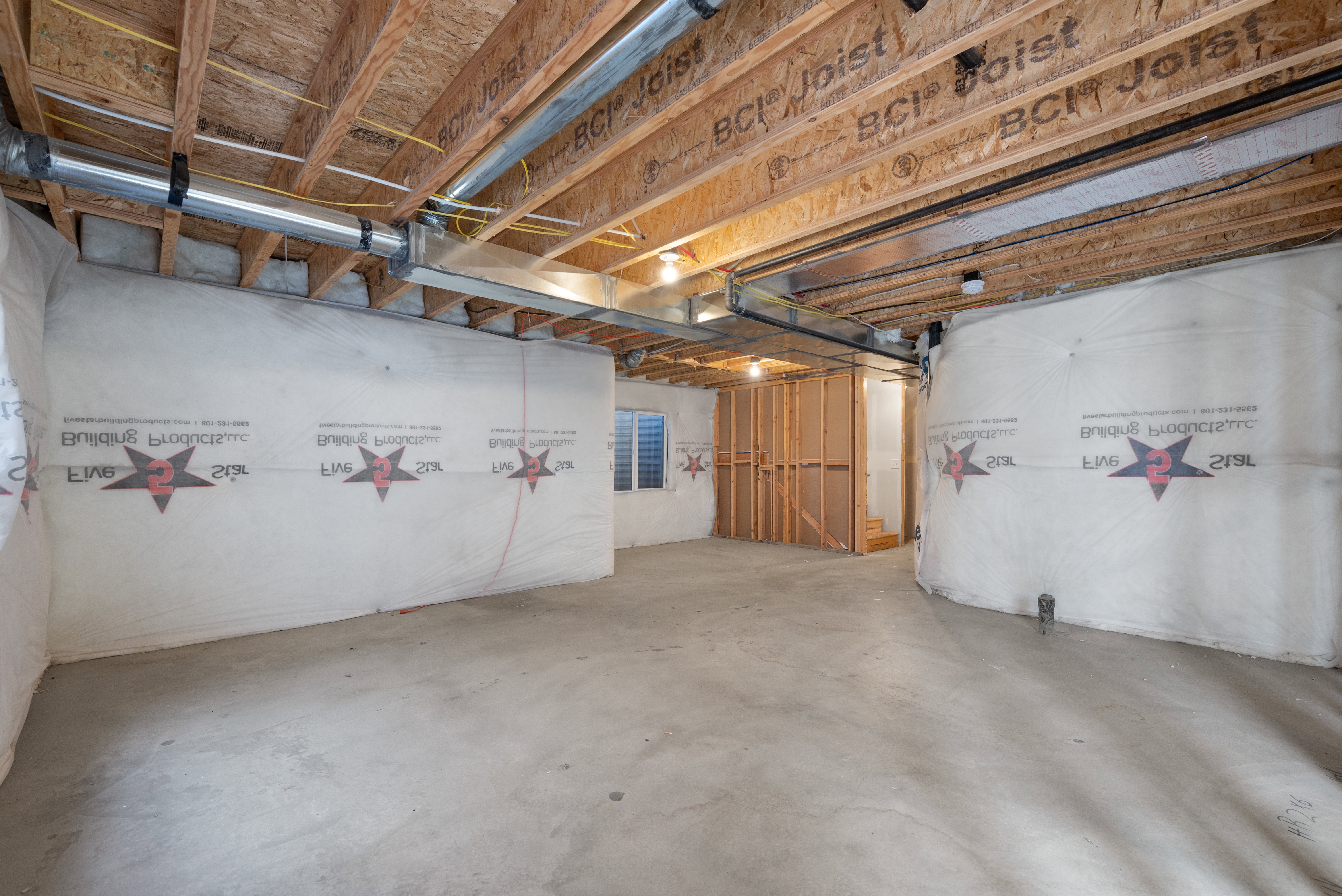 Unfinished basement featuring exposed wood joists and subflooring, insulated walls, concrete flooring, and partial framing